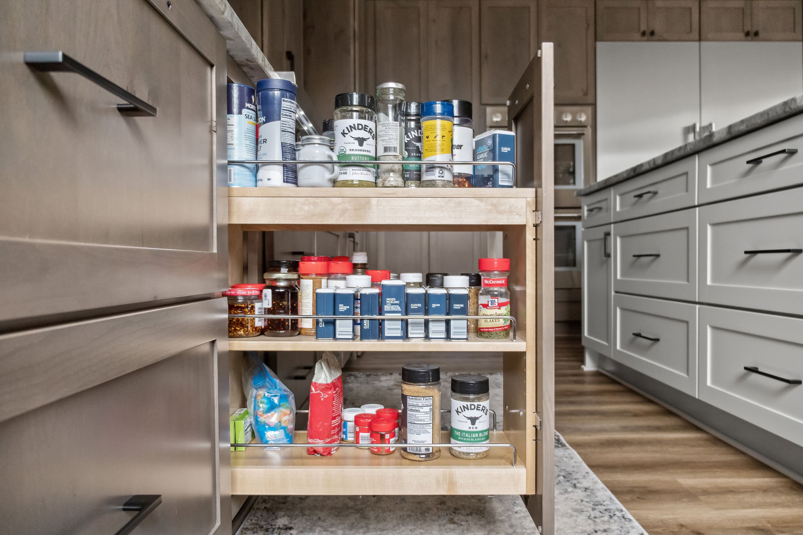 Double-tiered spice pullout cabinet fully extended, showcasing organized spices and pantry essentials.