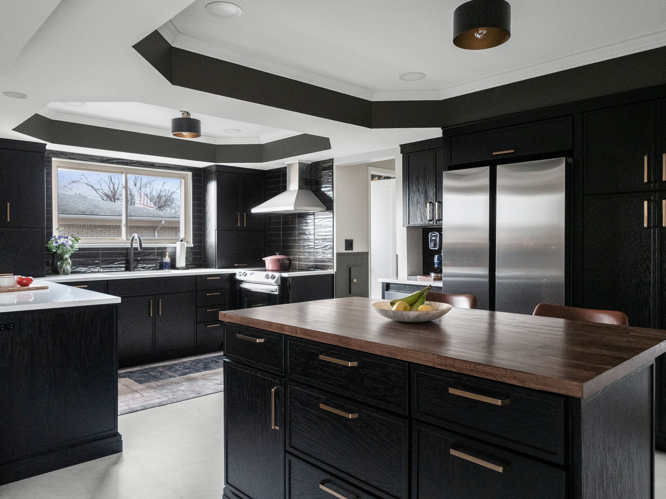 Dark and moody kitchen featuring Medallion Cabinetry Apollo door style in Oak painted Carriage Black Classic