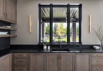 Dura Supreme Bria cabinetry in the Carson door style with quartersawn oak in Heather finish, leathered black quartz countertop
