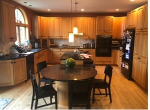 Existing kitchen featuring traditional raised panel cabinets and island with built-in dining area