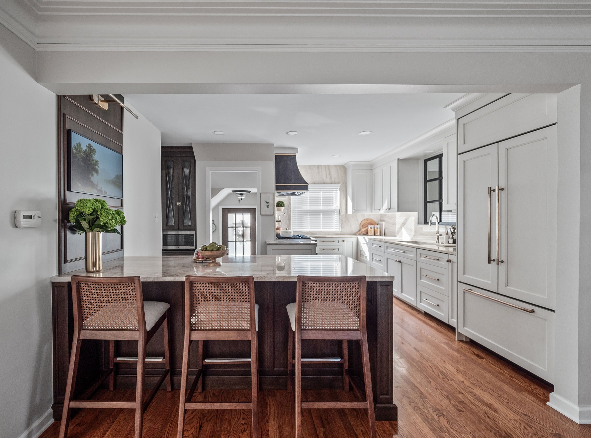 Kitchen with cabinetry in warm white and walnut finishes, antique brass hardware, and warm stone tops