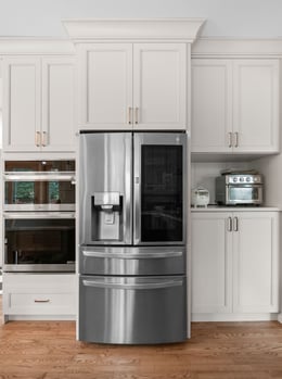 Masterpiece Cabinetry in Cottage paint on fridge wall; wall unit in base position at right allows for more storage below microwave shelf