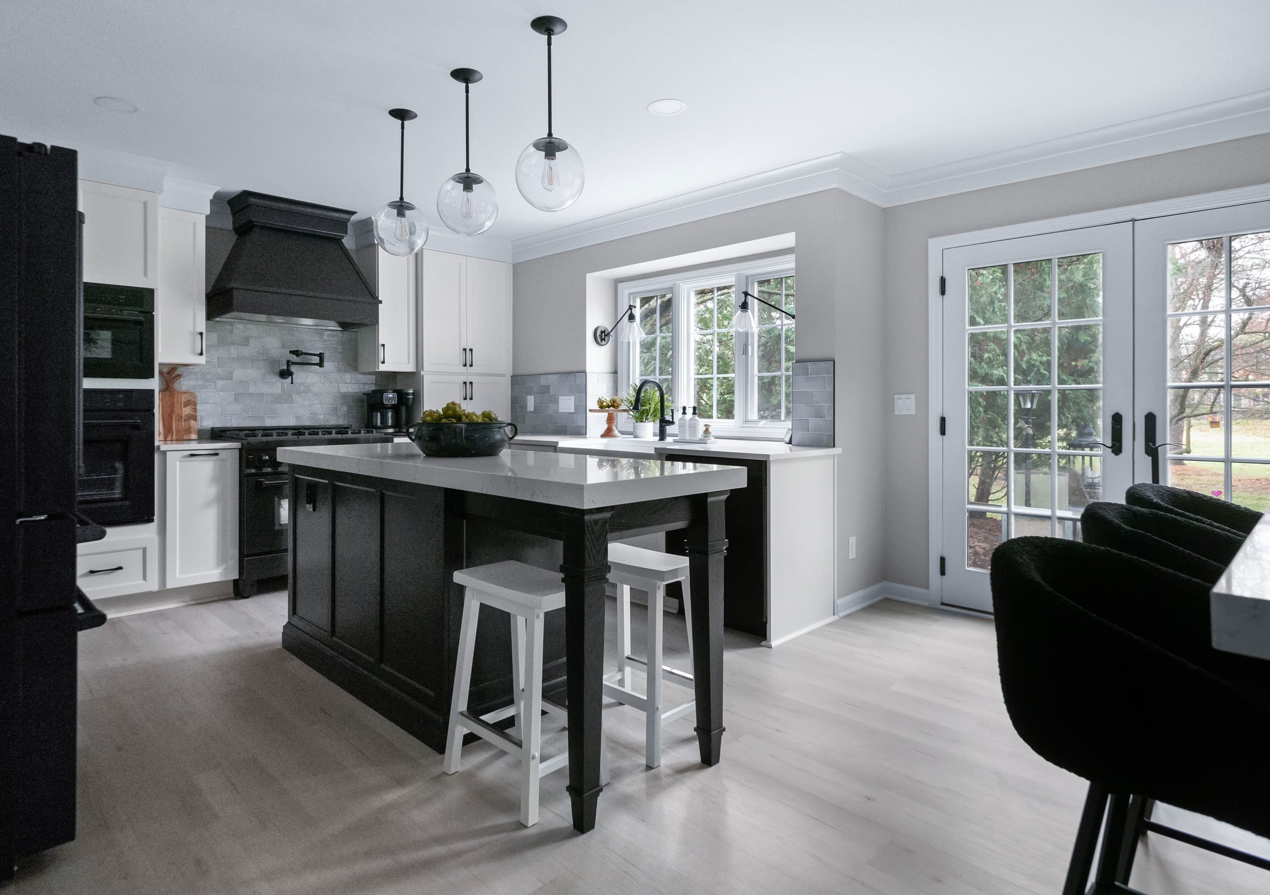 Medallion Cabinetry Wallace door style; island in Oak with Carriage Black paint; perimeter in Sea Salt White paint