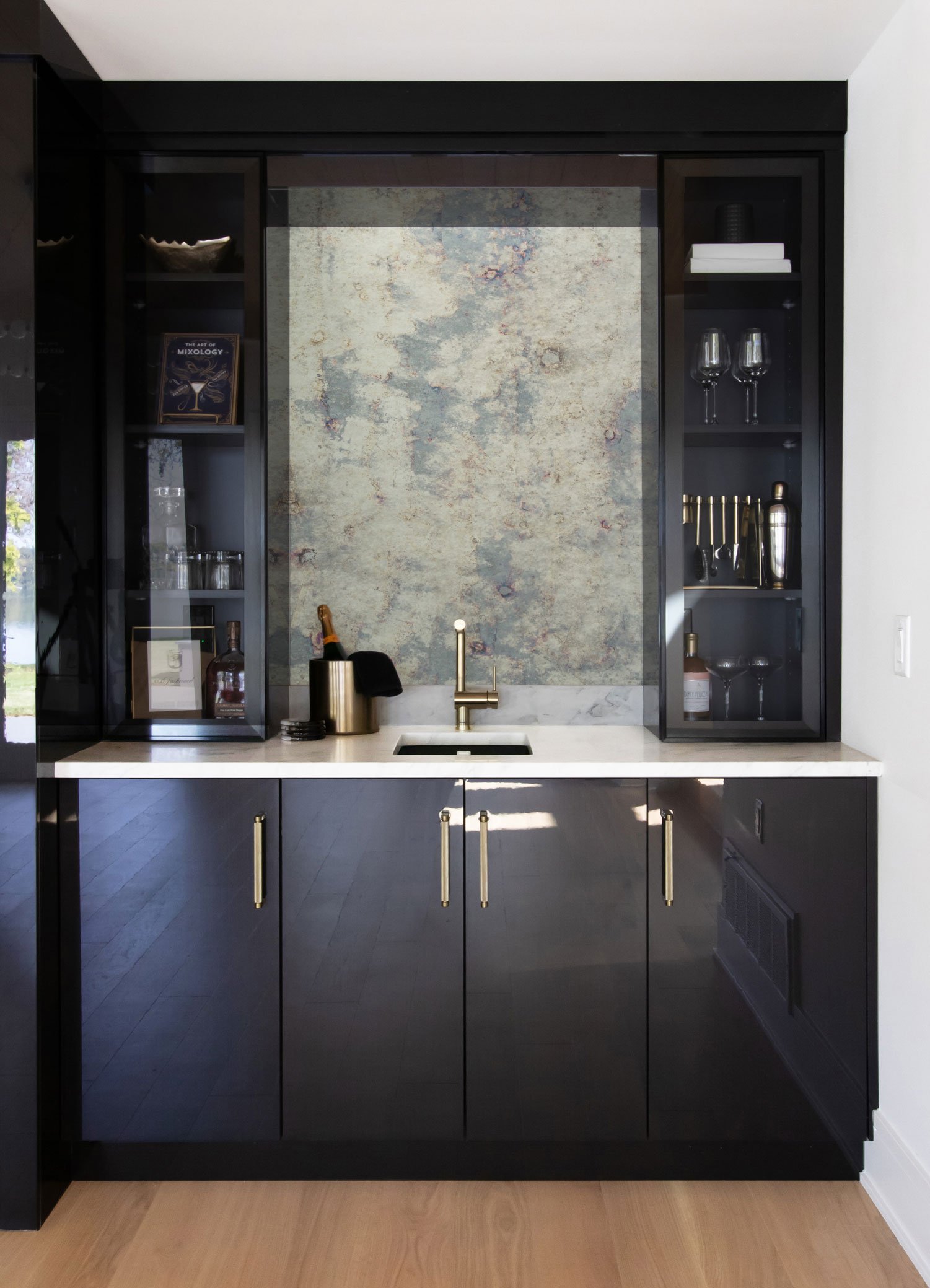 Wet bar featuring Inspira Cabinetry in the Vienna door style in Onyx with high gloss Wired Zinc finish