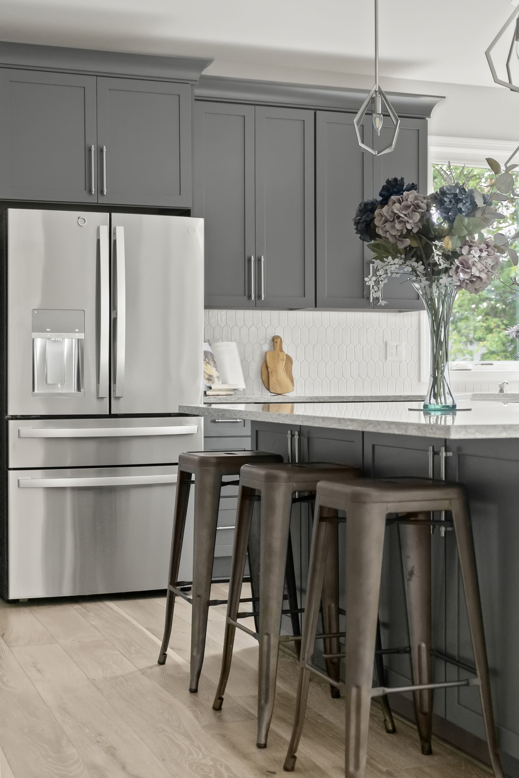 Modern kitchen with gray shaker cabinets, stainless steel appliances, and light wood floors creating an airy open layout.