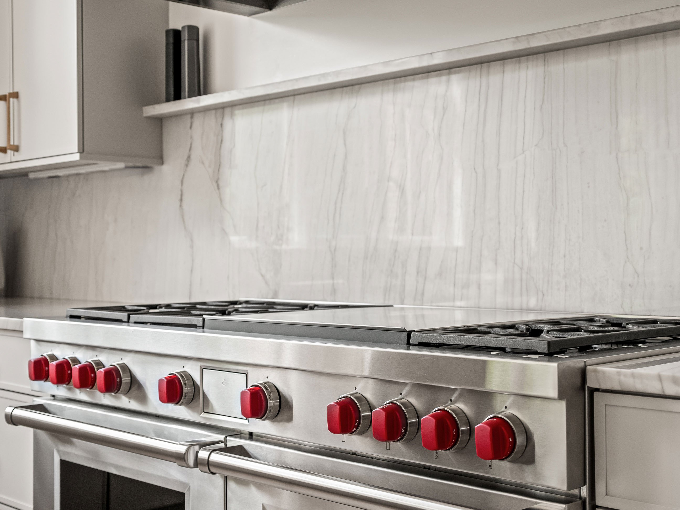 Kitchen featuring quartzite backsplash and shelf under statement hood with Wolf range