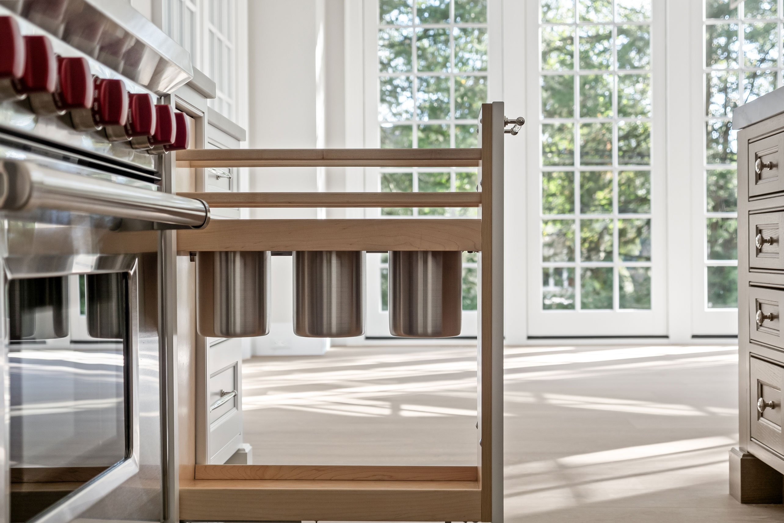 Pull-out utensil canisters adjacent to range in the kitchen.