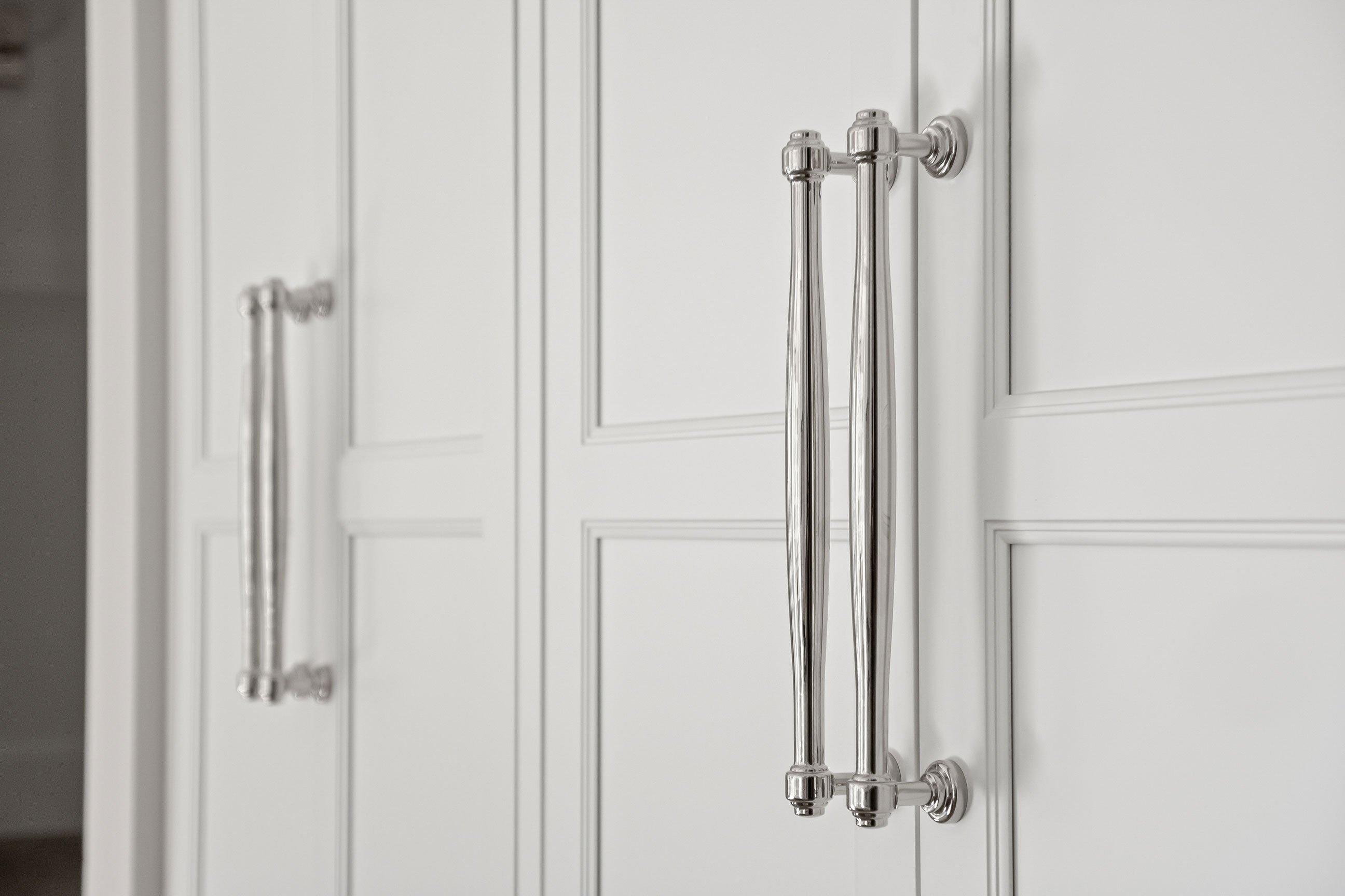 Inset cabinetry wall detail concealing pantry and refrigerator in kitchen.