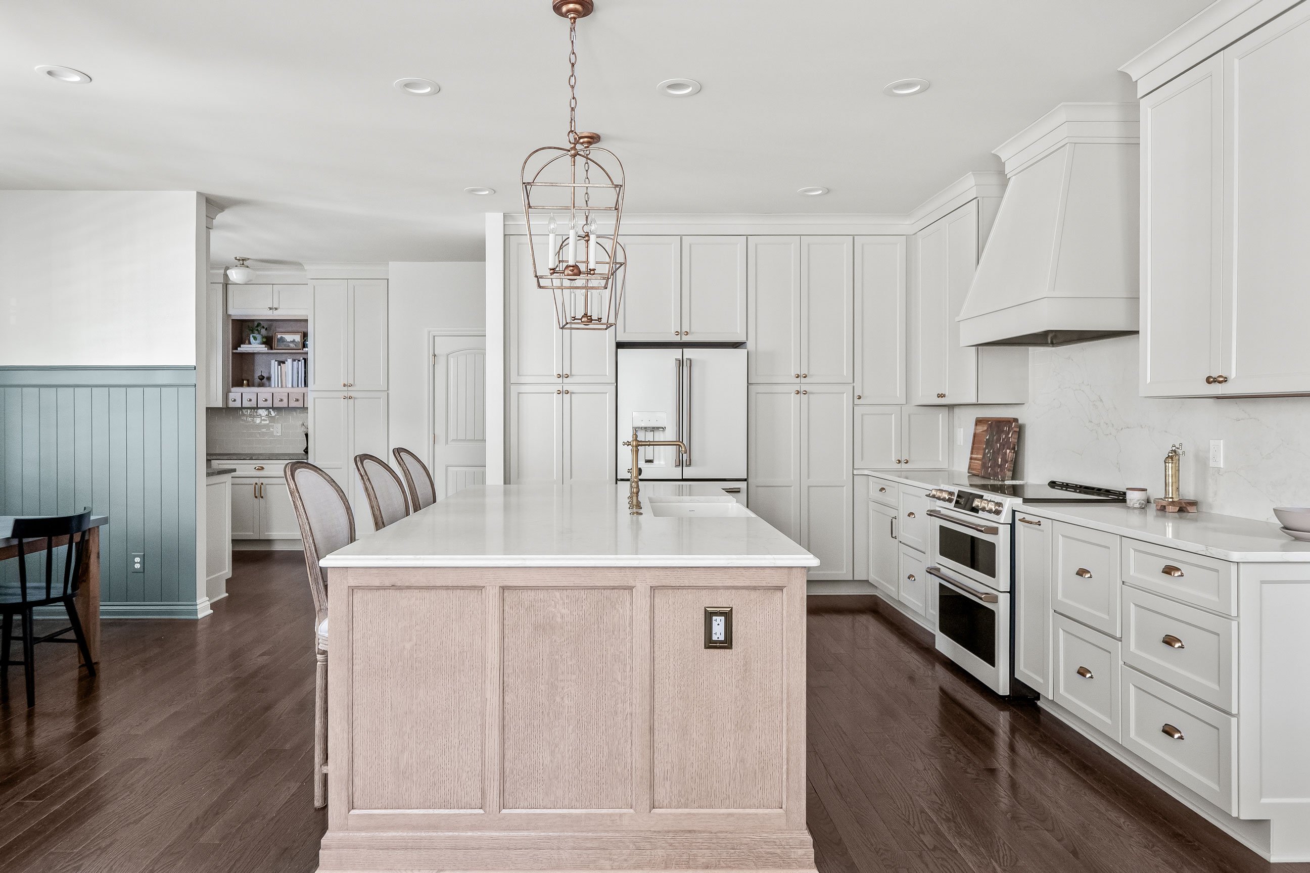 elegant remodeled kitchen with white shaker cabinetry, white oak island, and GE Cafe appliances