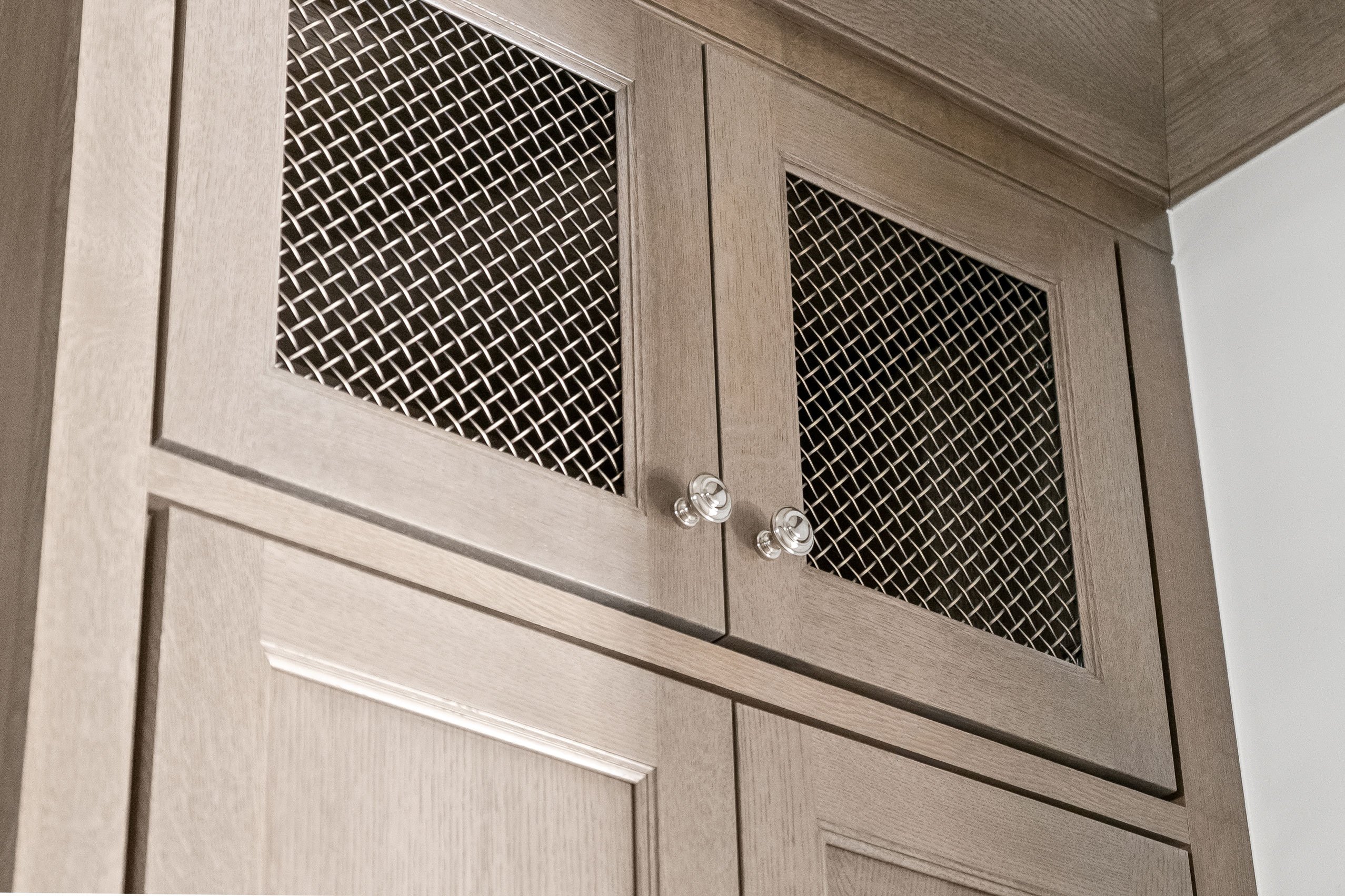 Detail of upper butler pantry cabinetry with decorative gold mesh inserts designed by KSI, adding texture and warmth to a neutral-toned space.