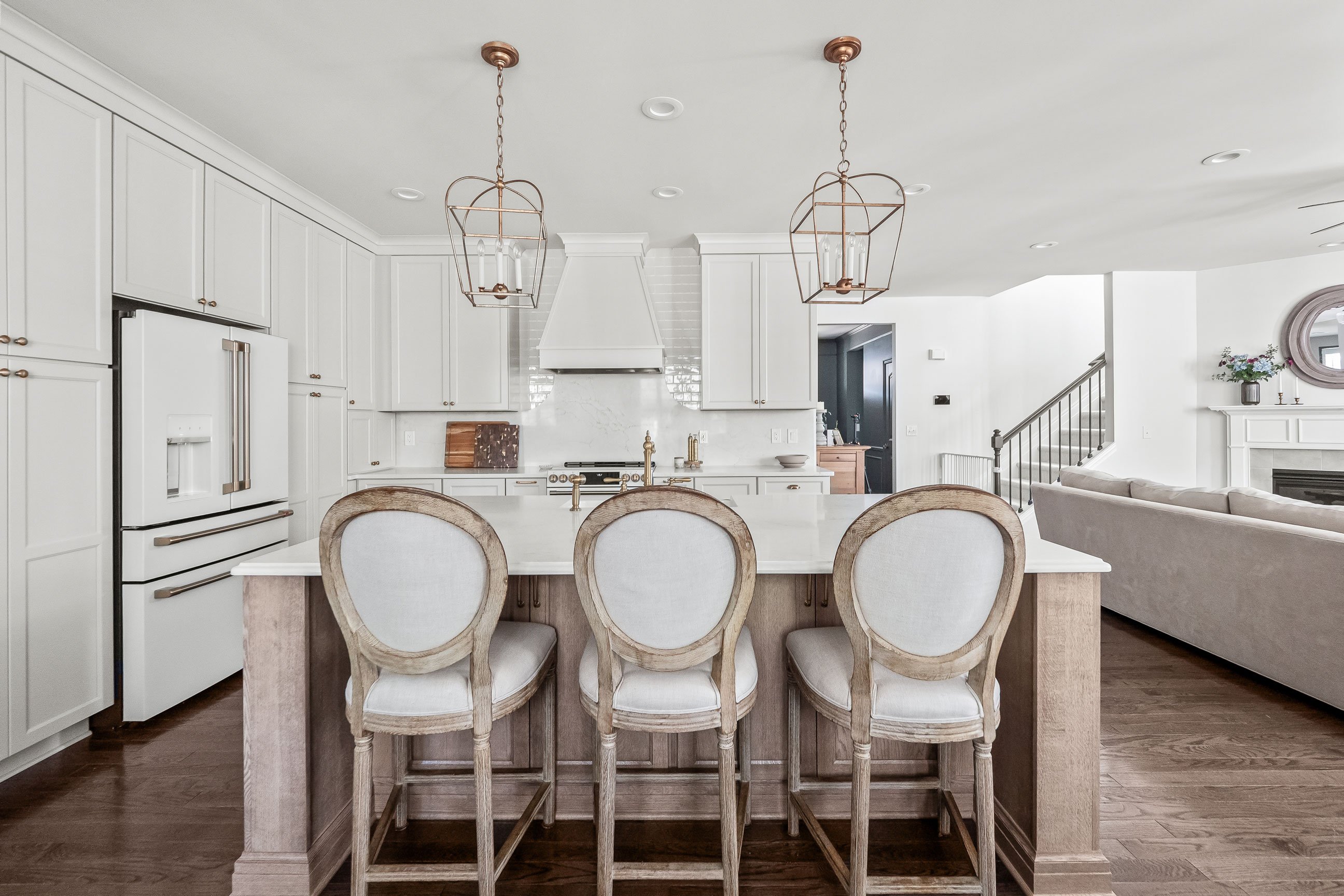 White Medallion cabinetry with Irish Crème finish, quartz countertops, and oak island with upholstered stools.