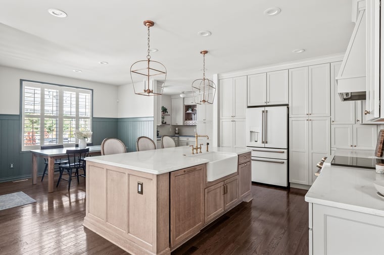 Kitchen remodel with large oak island, farmhouse sink, and dining nook with green wainscoting.