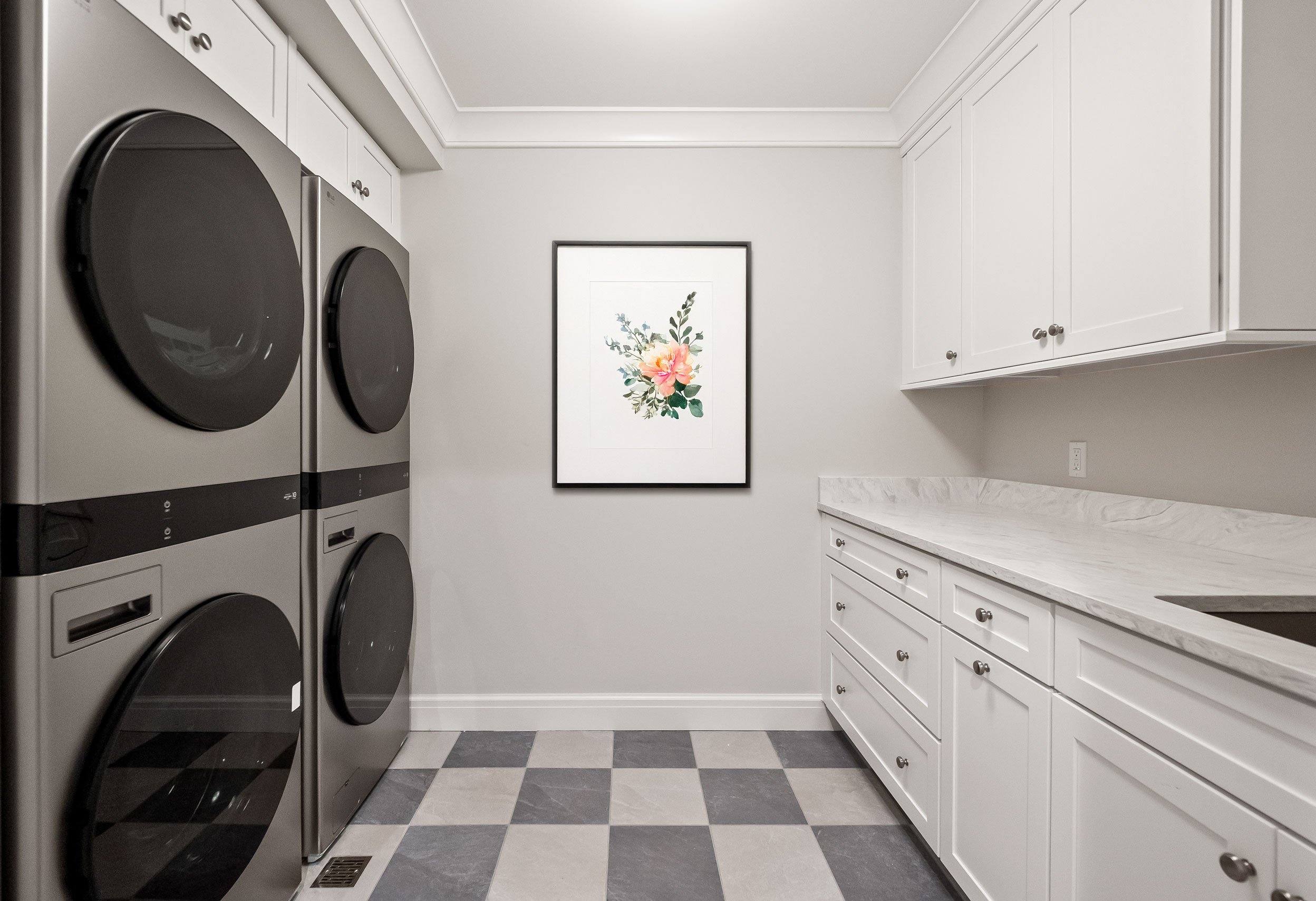 Laundry room with stackable washer and dryers, deep sink, and ample storage including a custom cleaning cabinet.