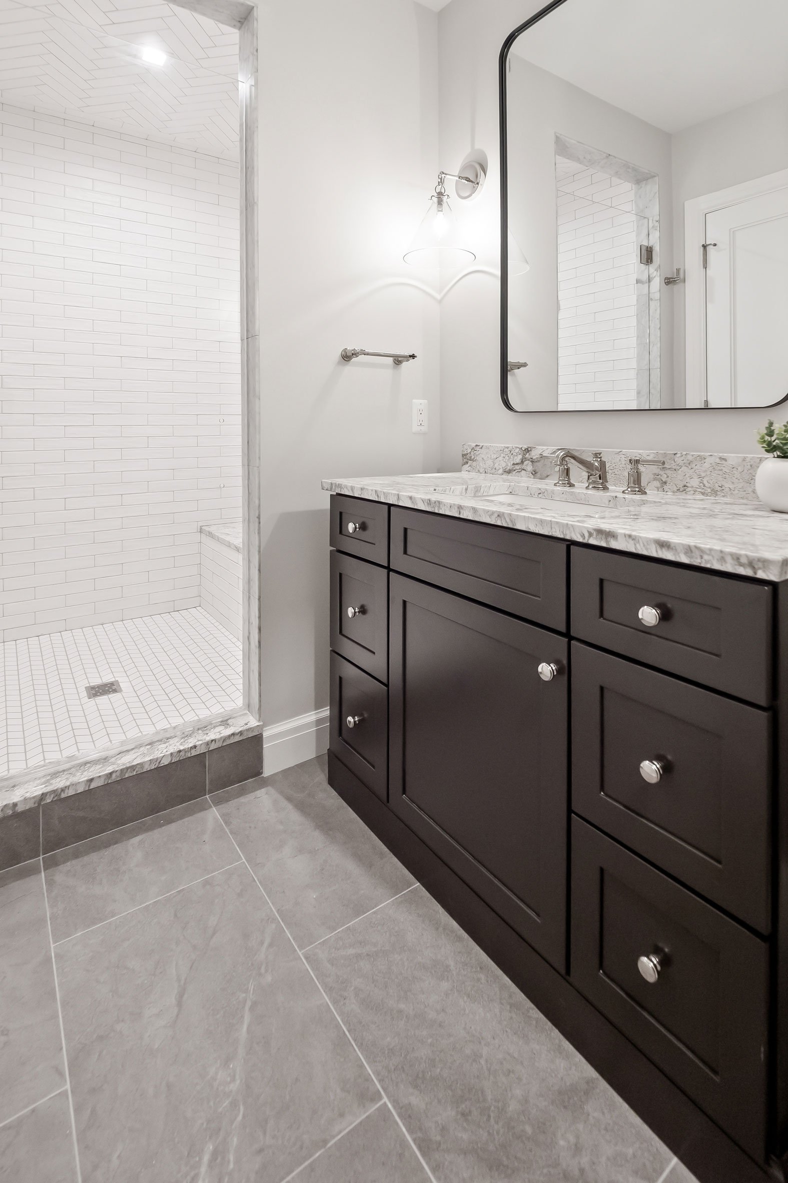 Basement bathroom featuring dark vanity cabinetry complementing the clean white tile shower.