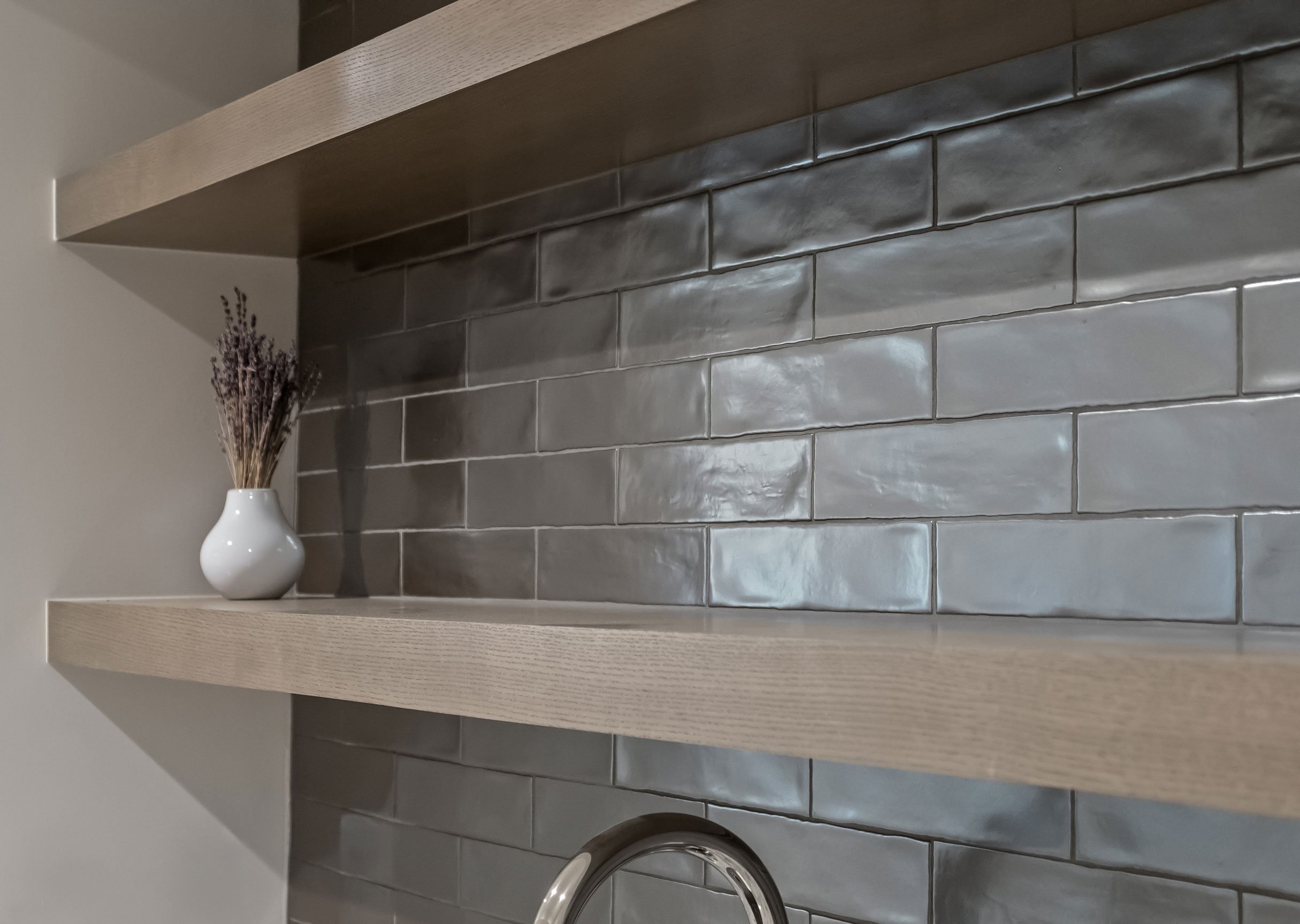 Floating shelves with gray tile in the lower level bar.