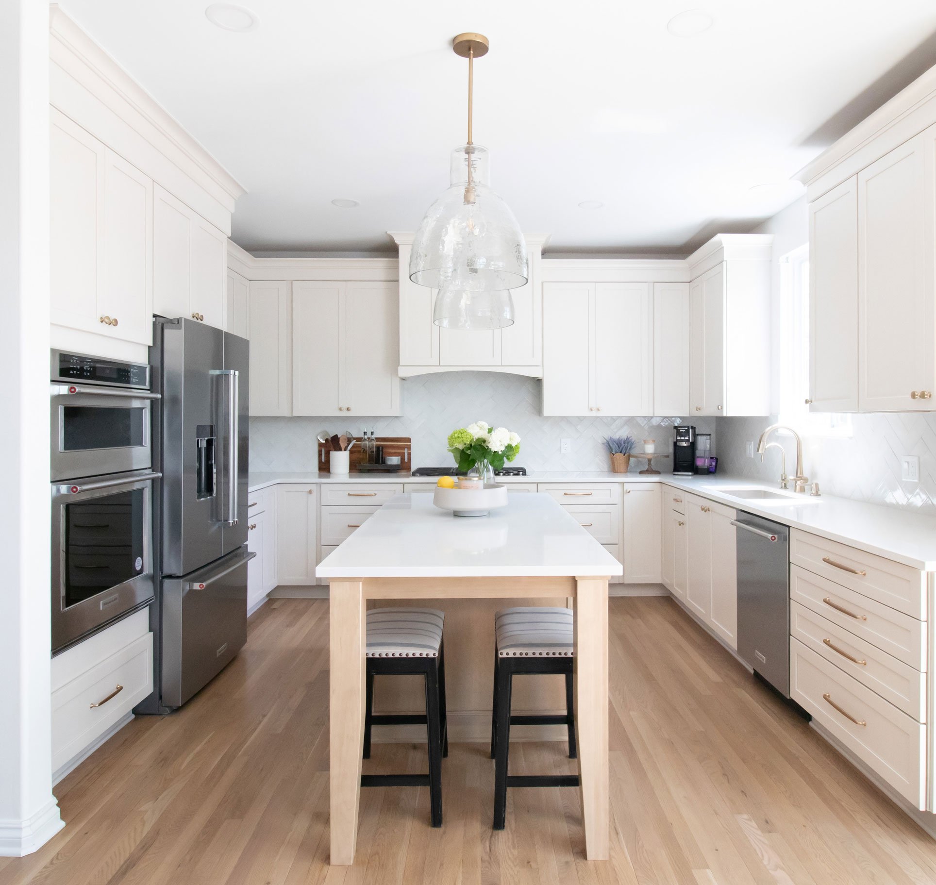 Cabinetry: Merillat Masterpiece Martel Door in Cottage Paint and Maple with Wicker Stain; Countertops: French Lace Quartz; Tile: Marazzi Rice Bianco 3x8 in herringbone pattern (kitchen), Artistic Tile Abbey Road Calacatta Gold Marble Mosaic, honed (butler's pantry)