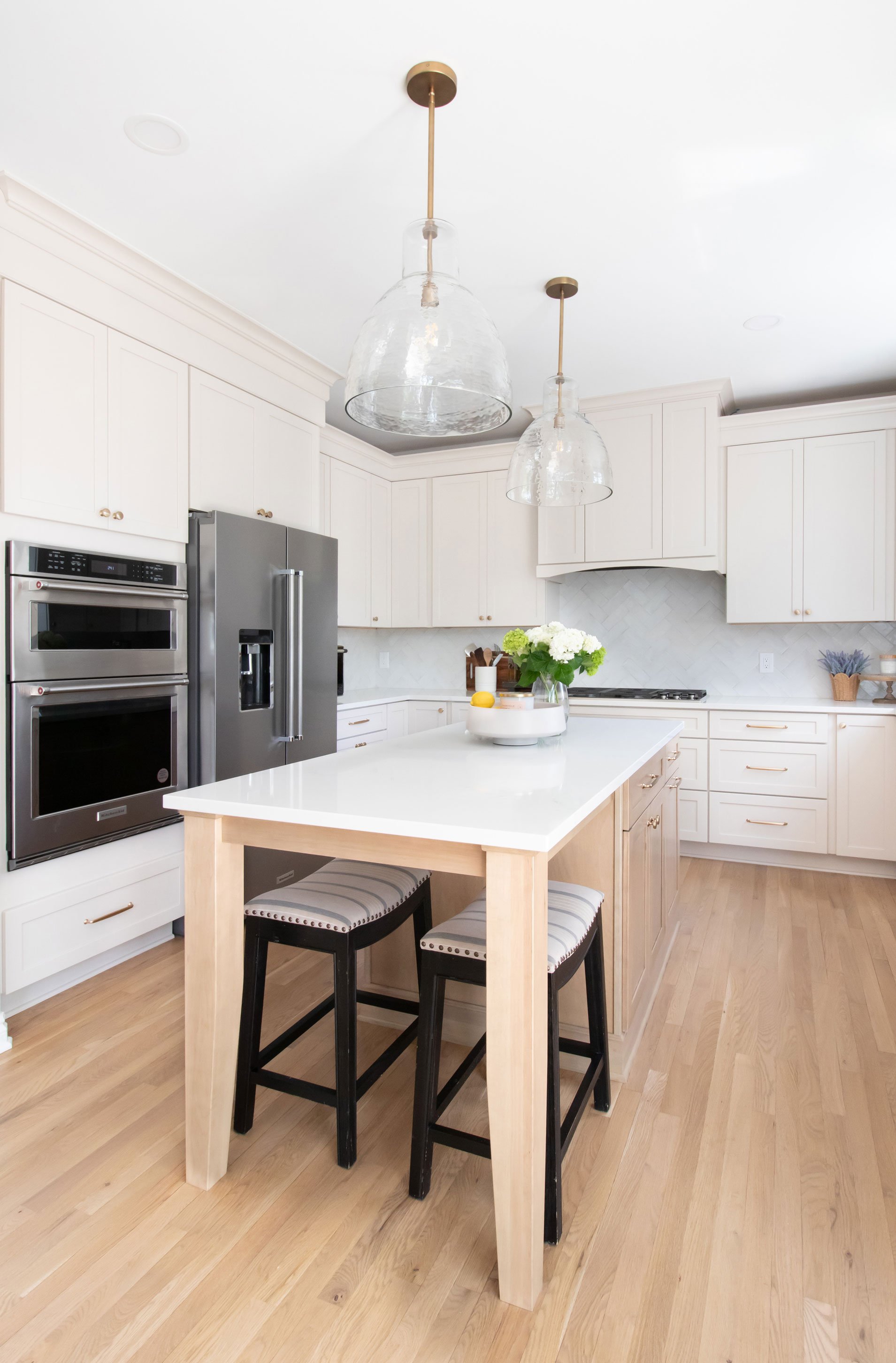 Cabinetry: Merillat Masterpiece Martel Door in Cottage Paint; Countertops: French Lace Quartz; Tile: Marazzi Rice Bianco 3x8 in herringbone pattern