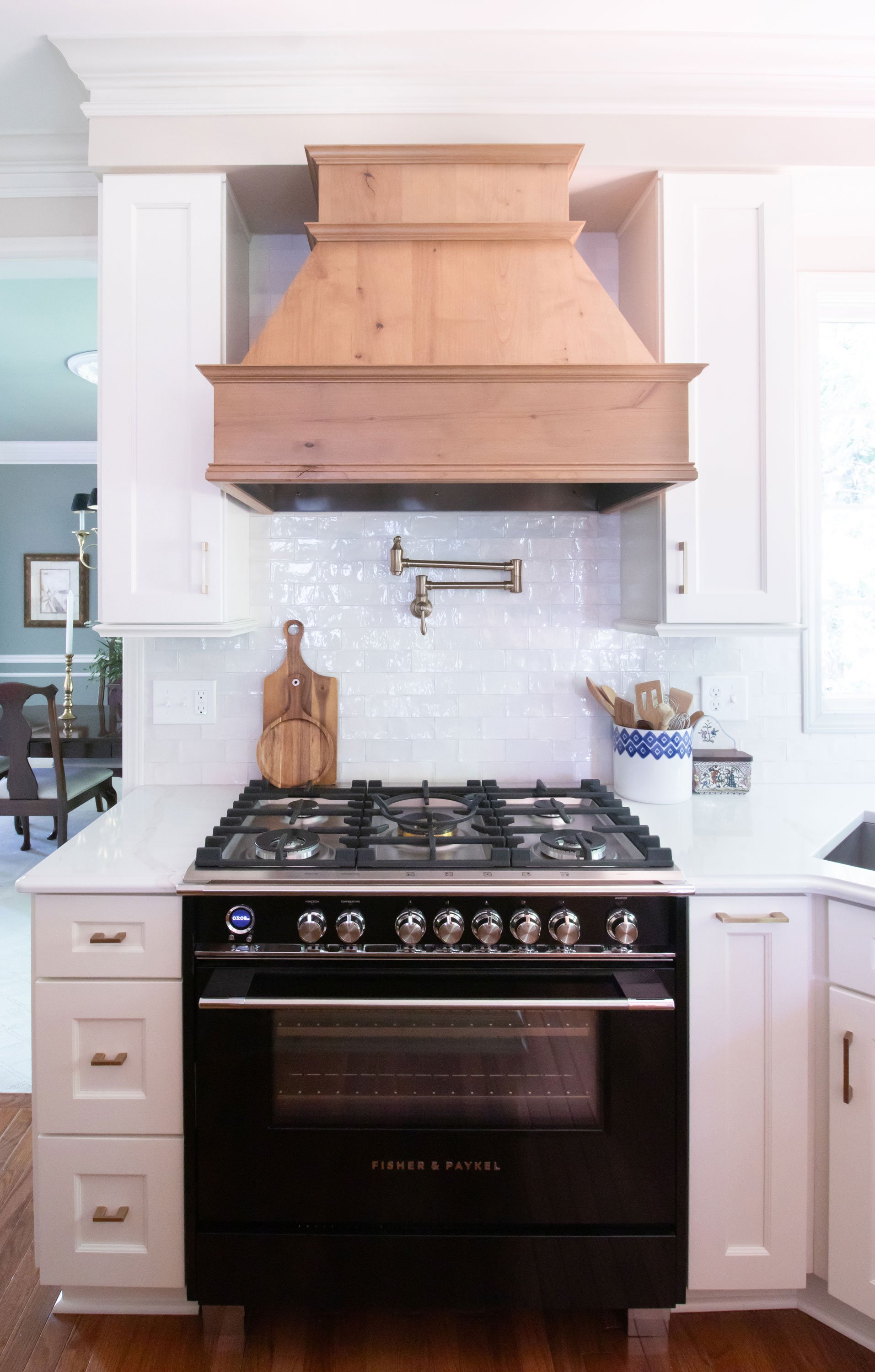 Chimney-style hickory hood with white cabinetry and black range