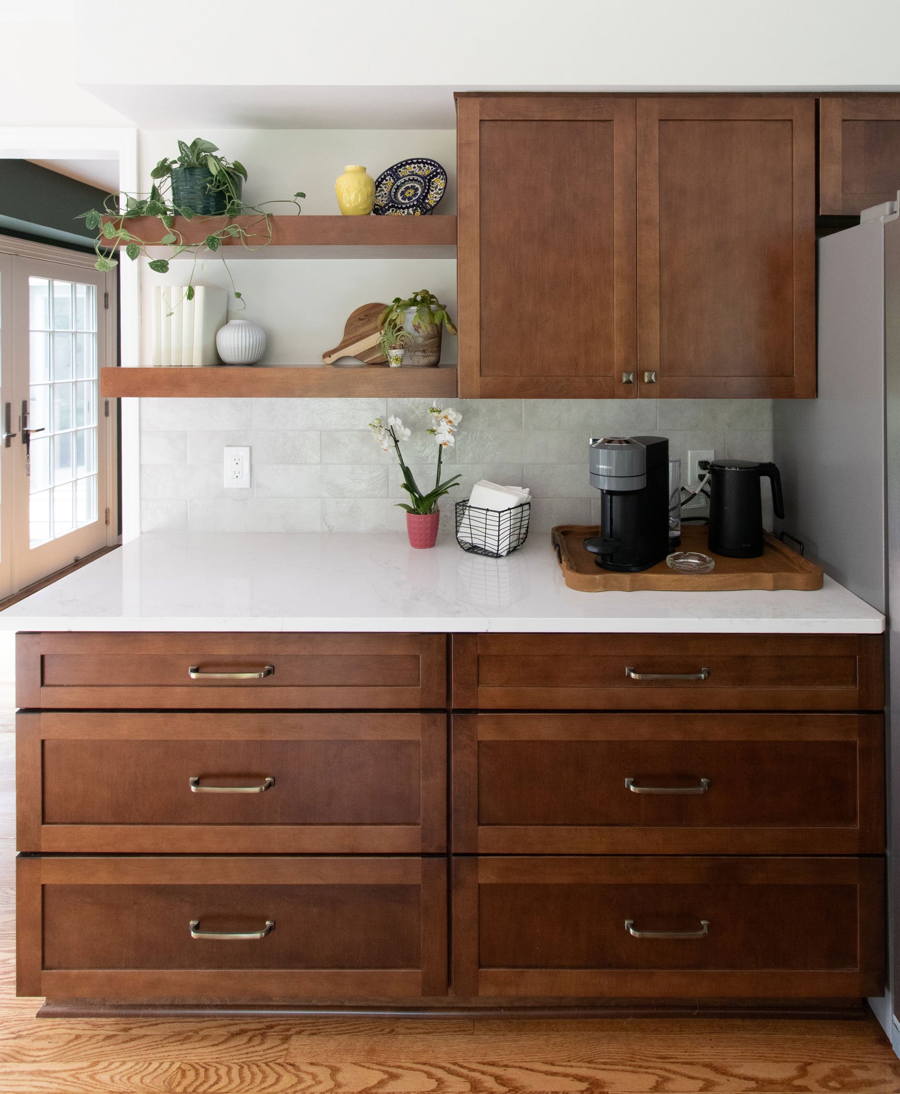 Floating shelves with decorative items above quartz countertop and subway tile backsplash.