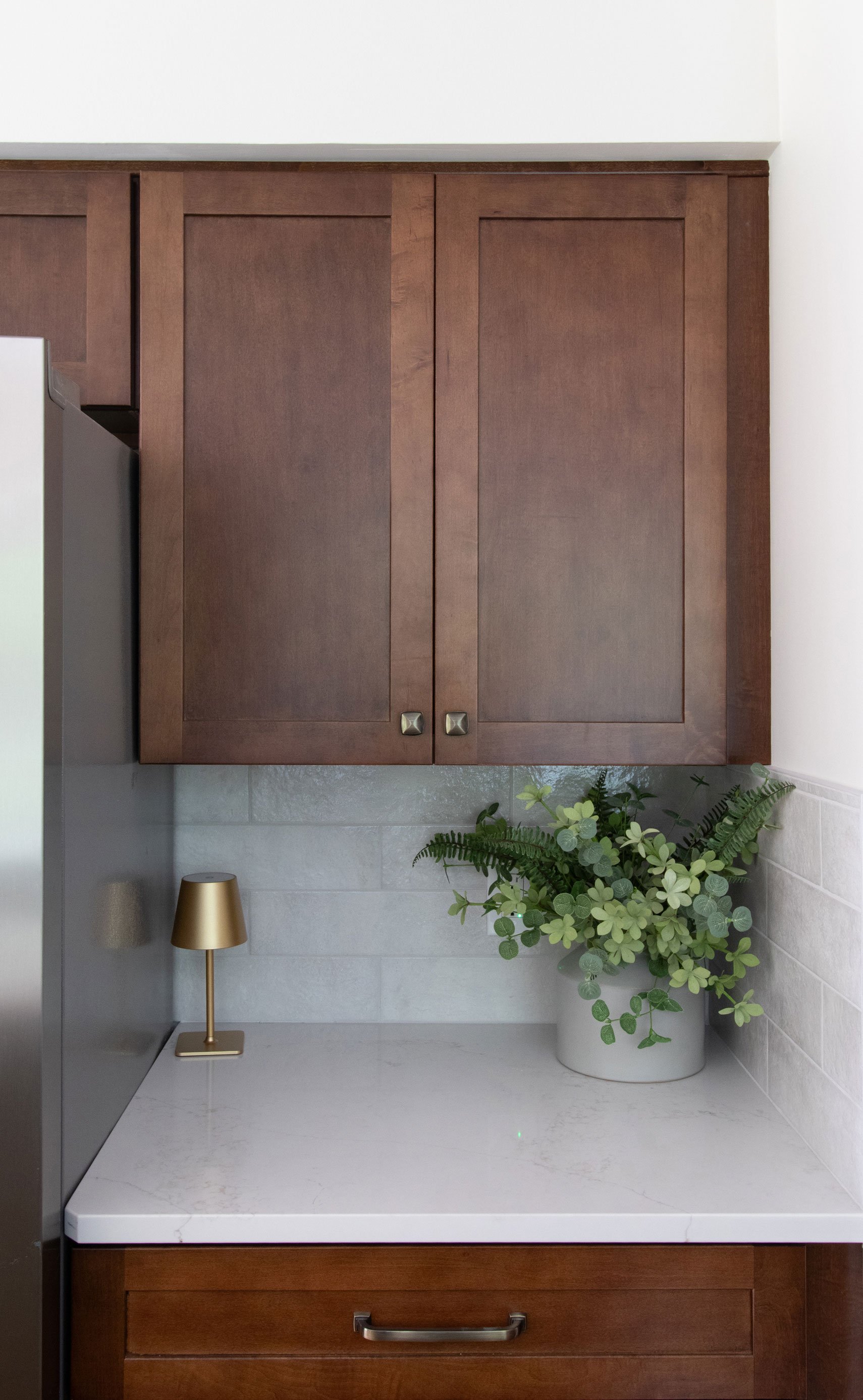 Merillat Masterpiece cabinetry in the Martel door style, featuring maple wood in Cognac finish and white quartz countertops.