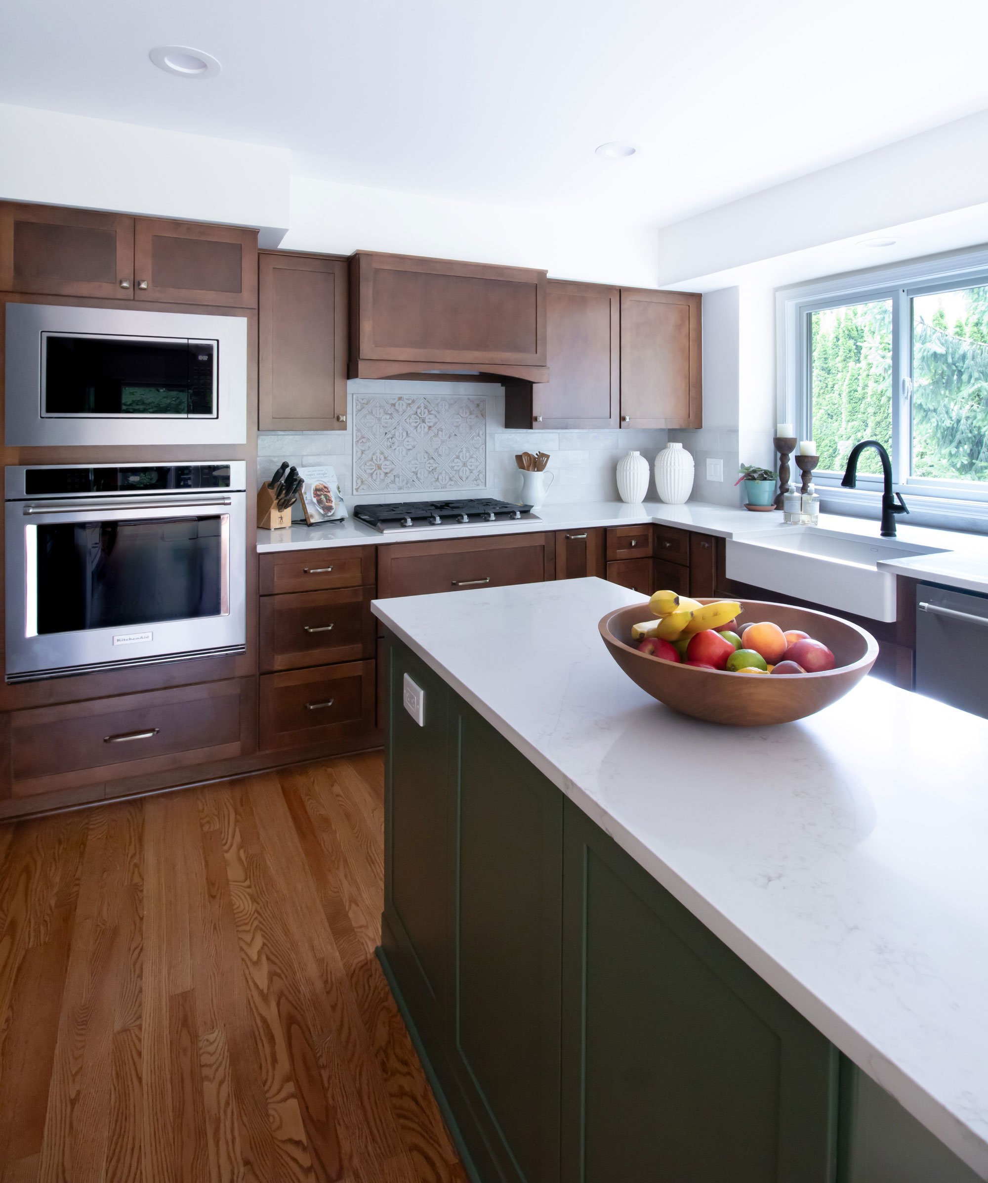 Angled view of kitchen showcasing green island and wood stained cabinetry from Merillat Masterpiece.