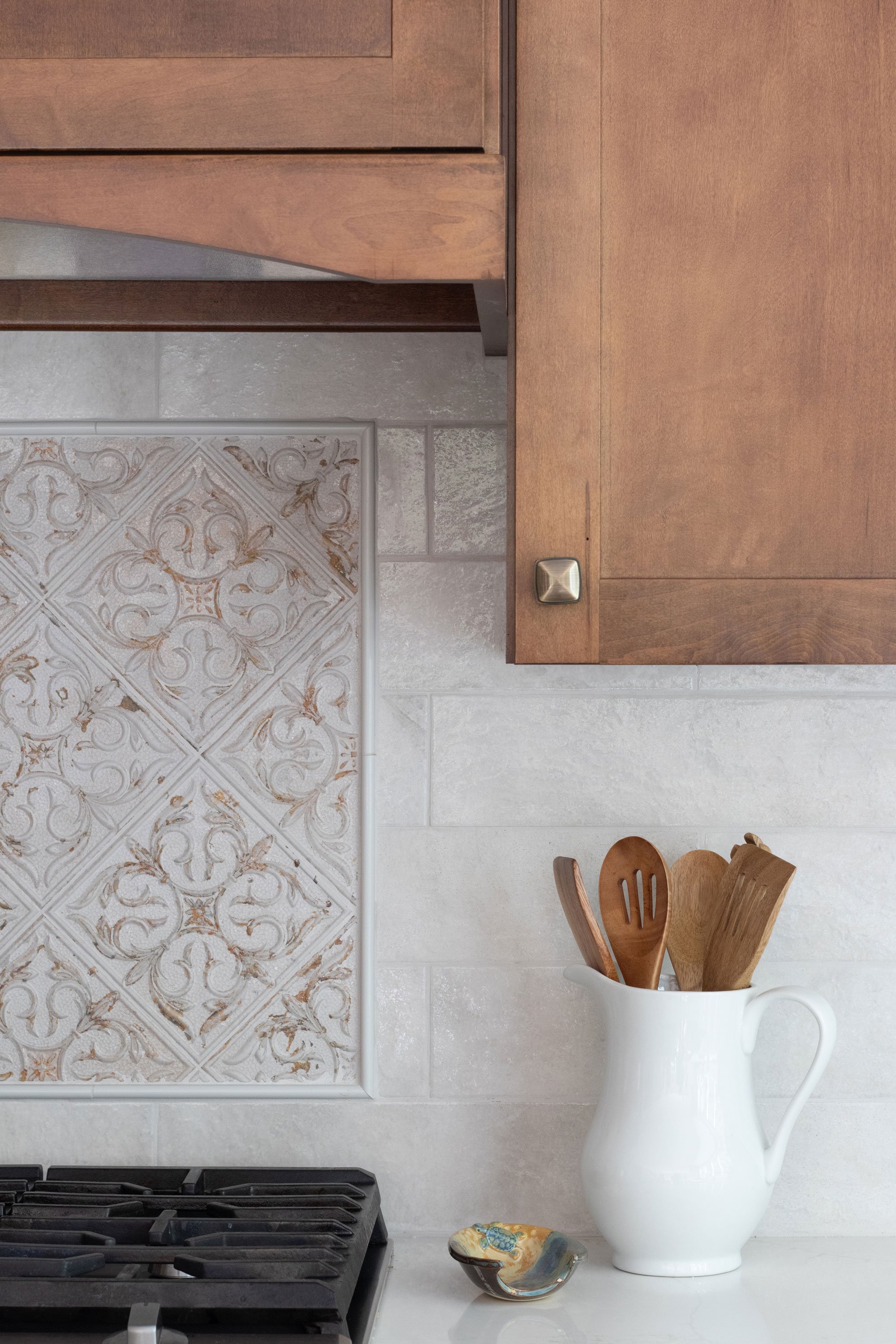 Close-up of cooktop wall with decorative patterned backsplash tile.