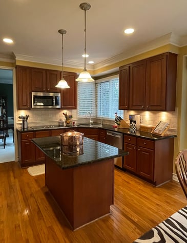 Before kitchen image with dark cherry raised panel cabinetry and black countertops