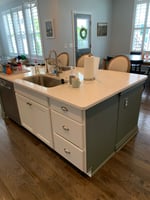 Kitchen island pre-remodel, with builder-grade cabinetry and drywall construction