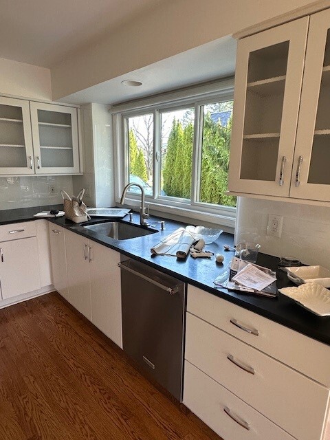 Original kitchen featuring white cabinetry with glass doors and black countertops around sink area.