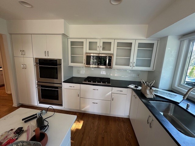Tall white cabinetry with double ovens in original kitchen layout.