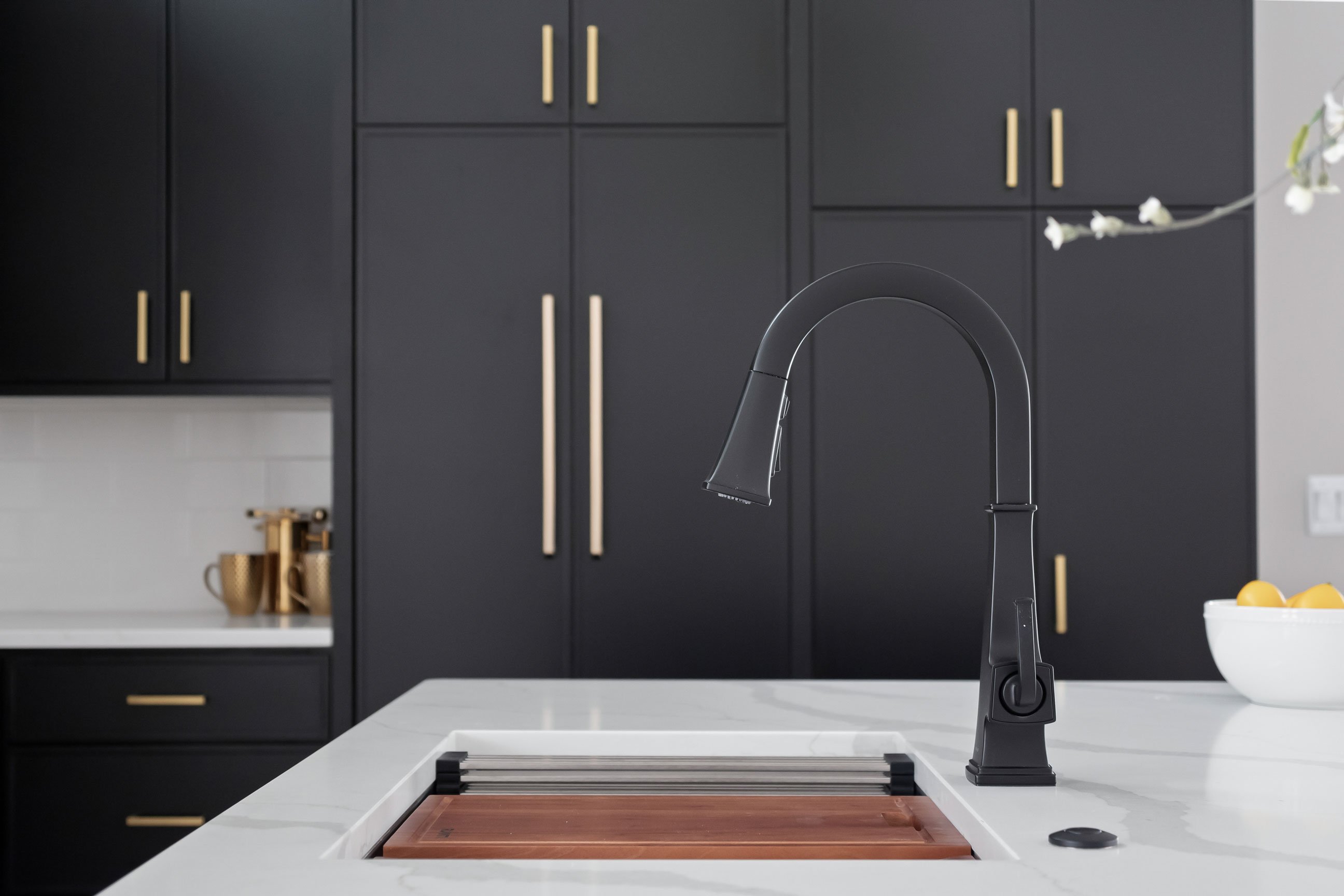 Ruvati workstation sink with walnut cutting board and integrated accessories in dark moody kitchen design