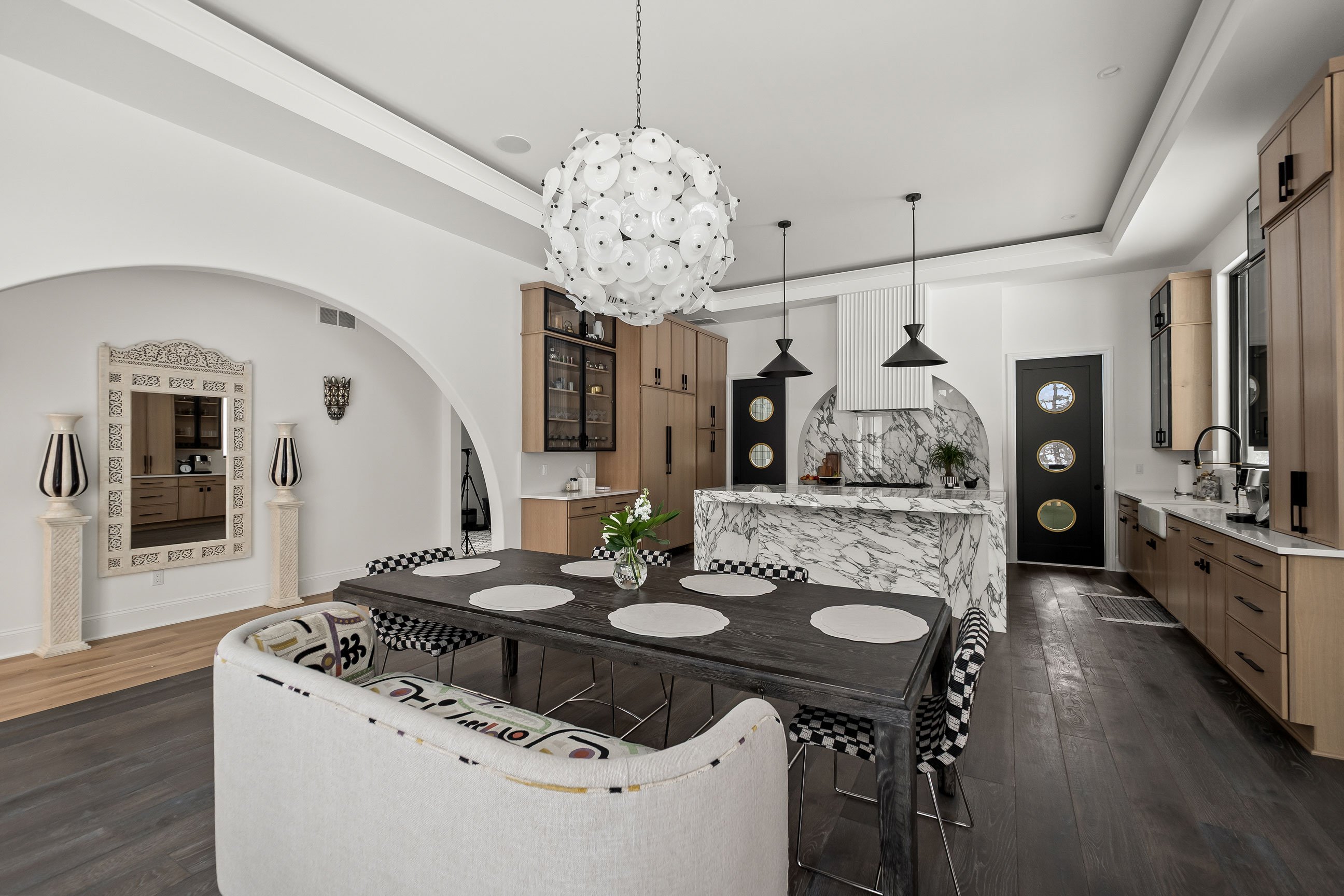Spacious kitchen featuring quartersawn white oak cabinetry, metal-framed glass upper cabinets, and a large island with waterfall stone top.