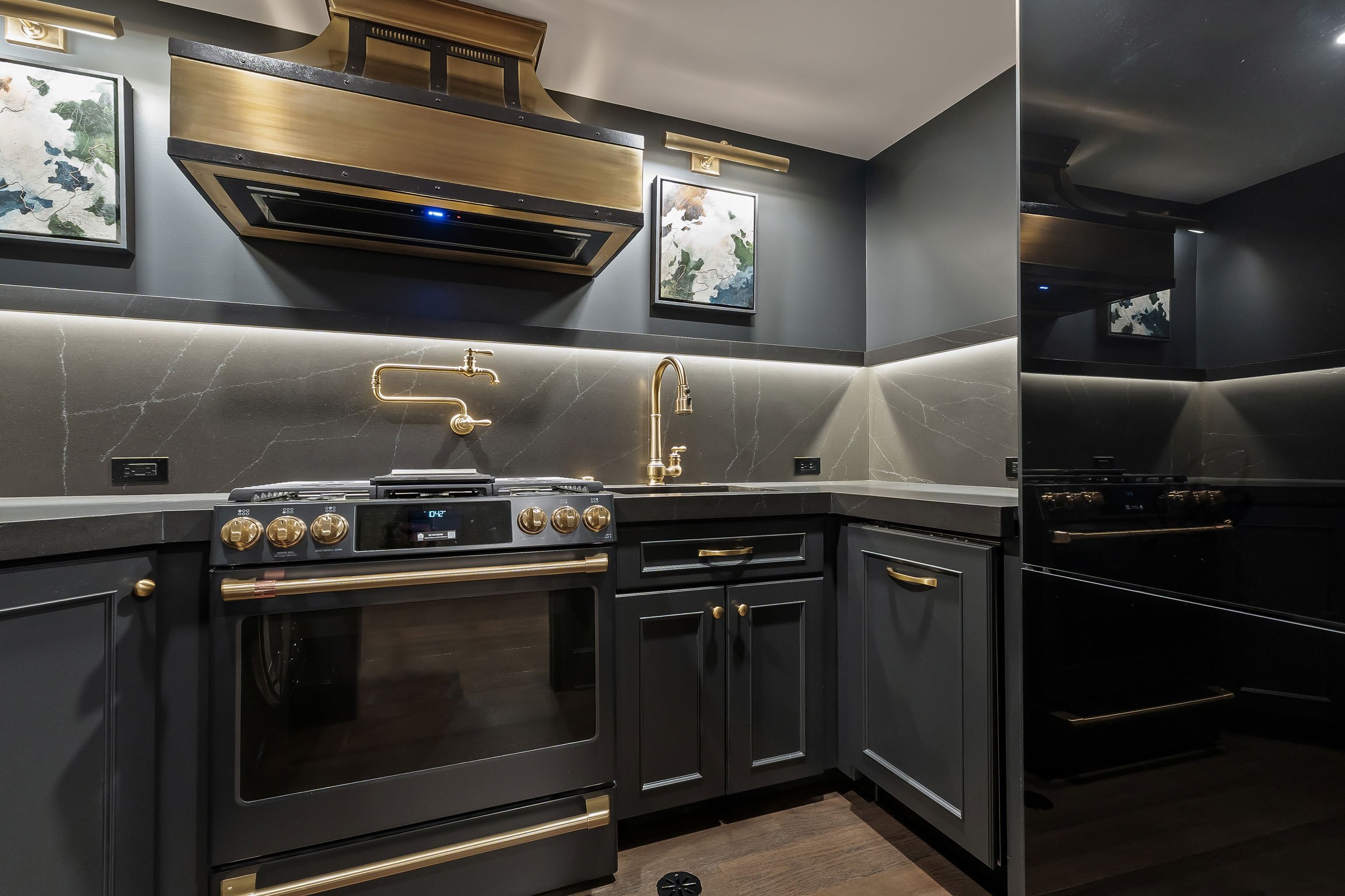 Multi-functional basement kitchen combining laundry appliances, custom cabinetry, brass hardware, and entertaining amenities.