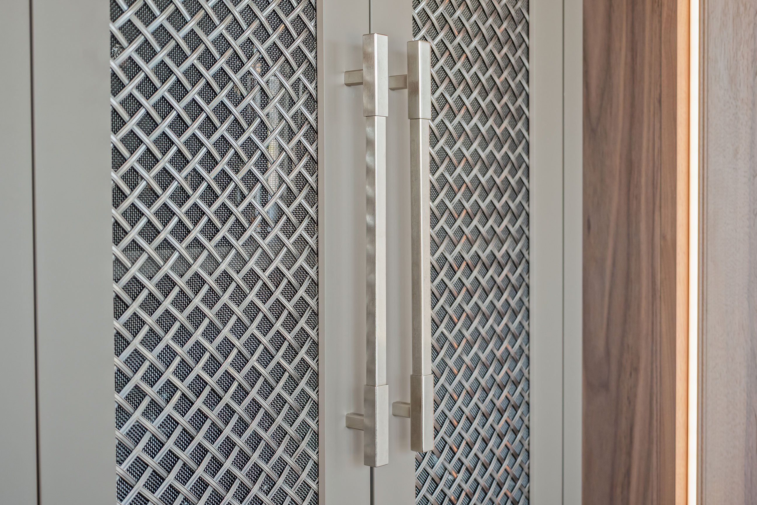Mesh inserts in gray painted cabinetry