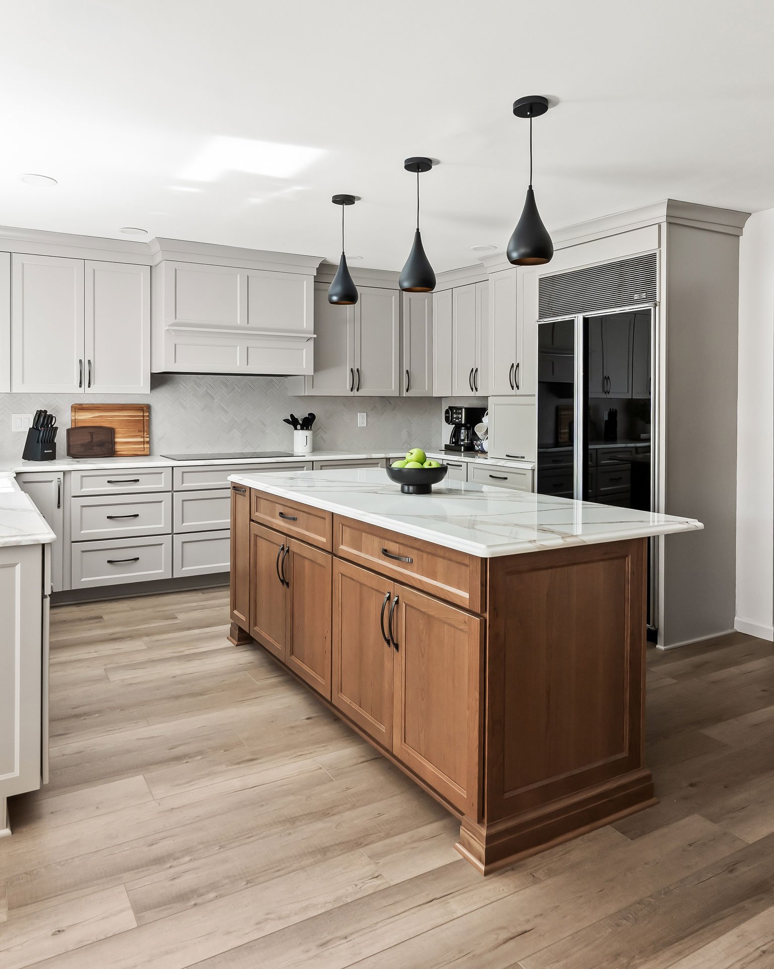 Another angle of the kitchen island, showing the two-tone cabinetry and open sightline to the refrigerator and cabinetry wall.