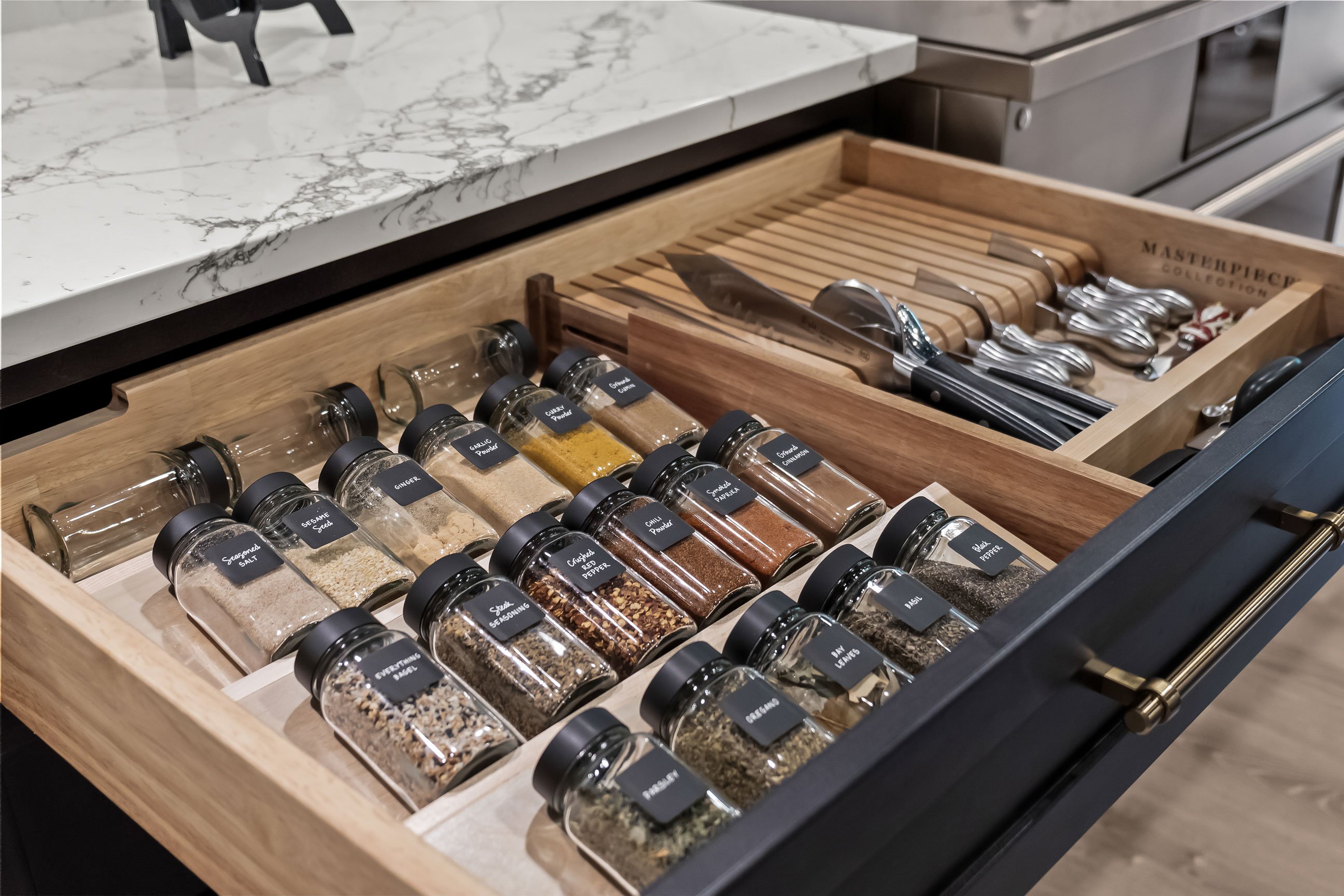 Pull-out spice drawer in dark cabinetry with light quartz countertop