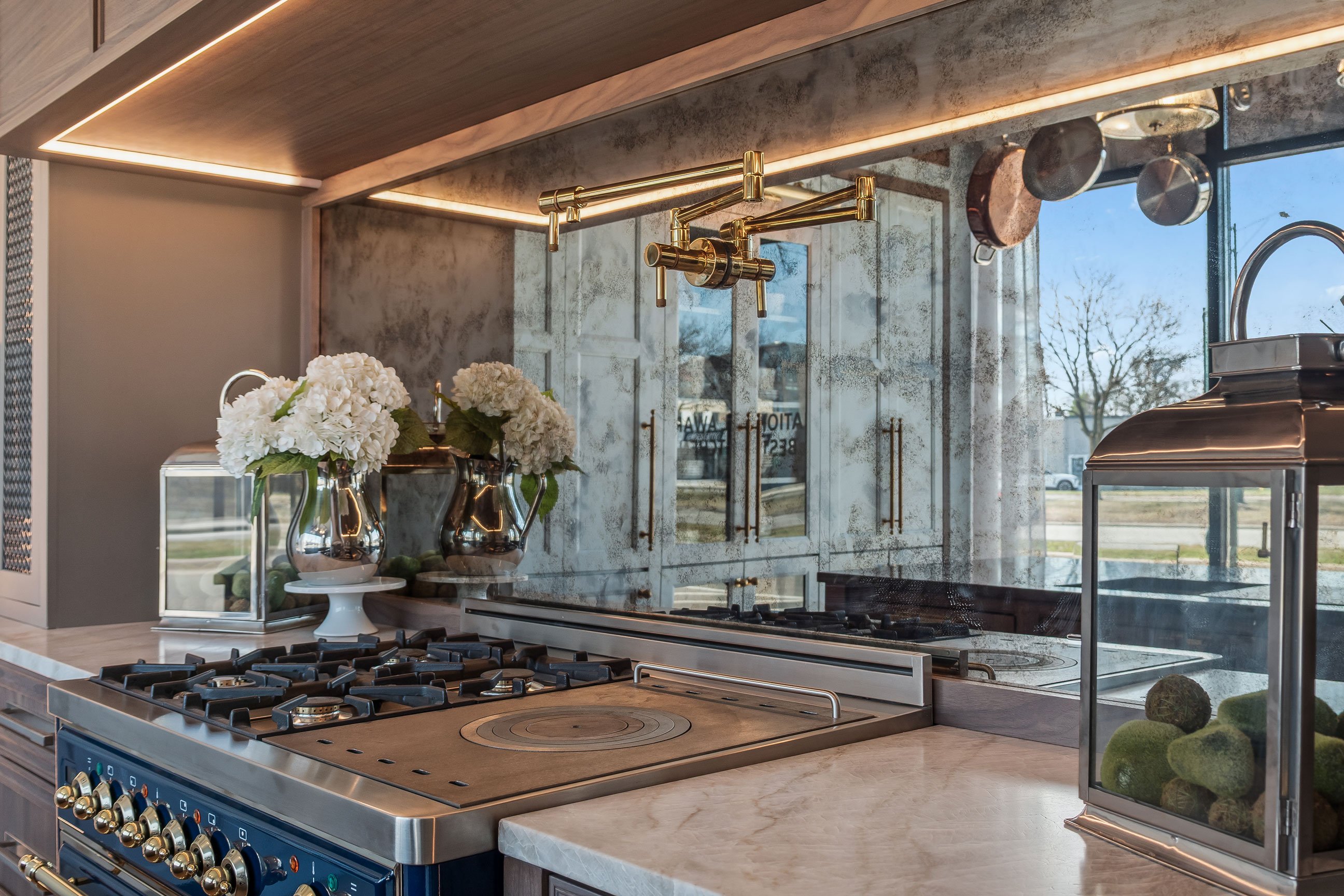Antique glass backsplash under walnut statement hood, flanked by gray painted tower cabinetry