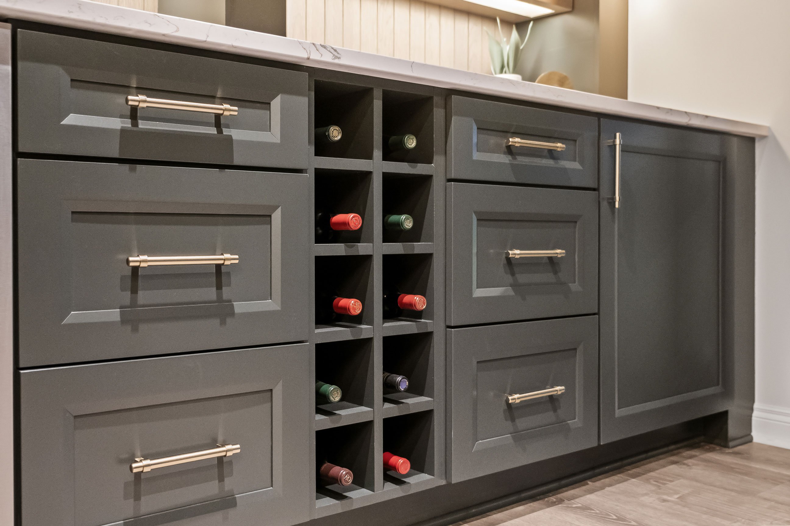 Dark painted cabinetry with gold accents in basement bar