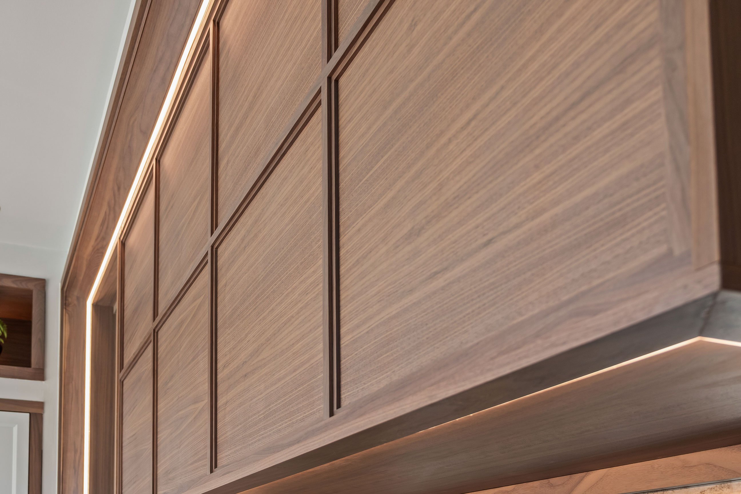 Large crown with accent lighting creating a theater effect over a walnut statement hood