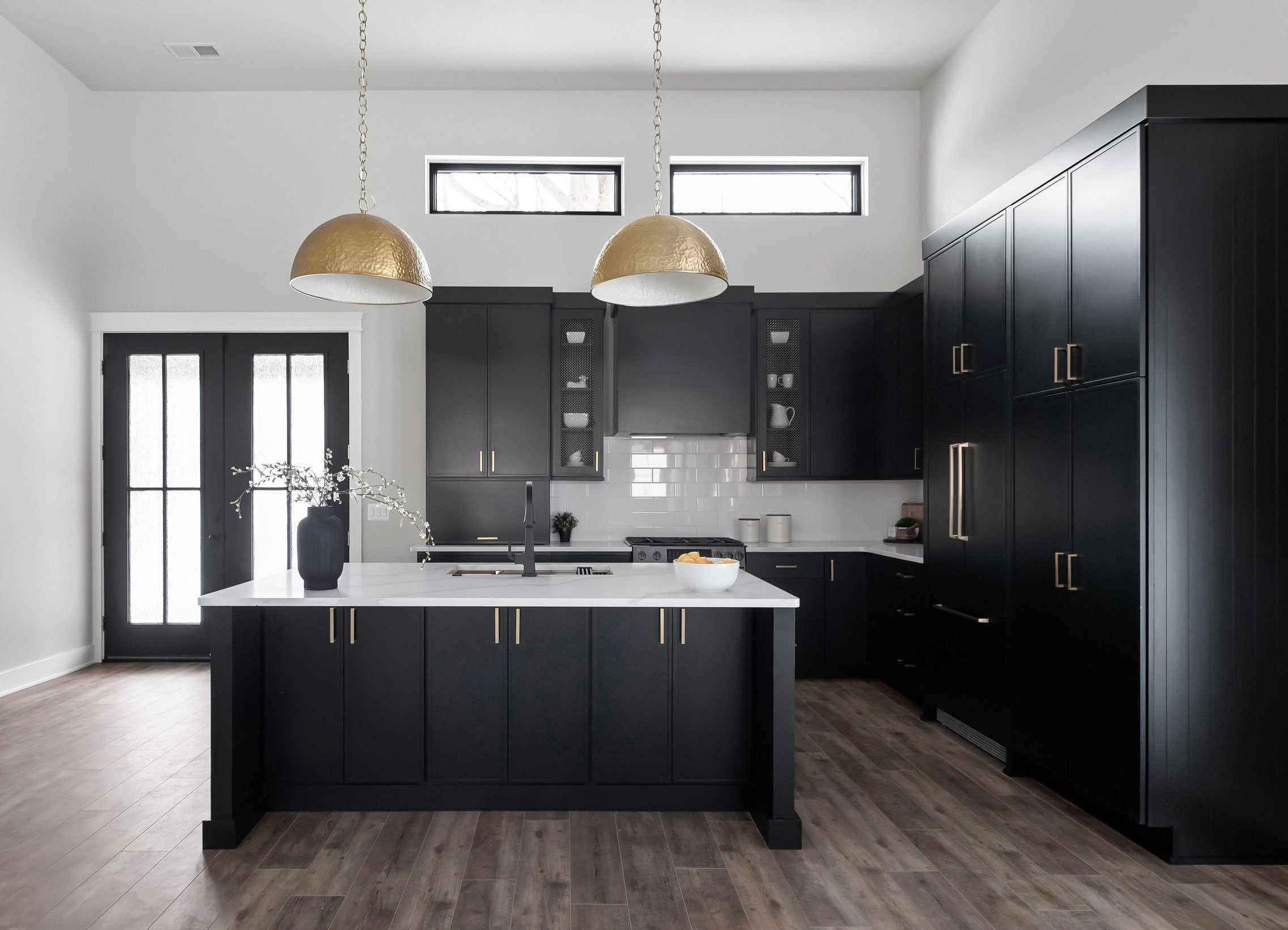 Barndominium kitchen featuring 14-foot ceilings, paneled refrigerator, black cabinetry, v-groove paneling, and gold hardware accents