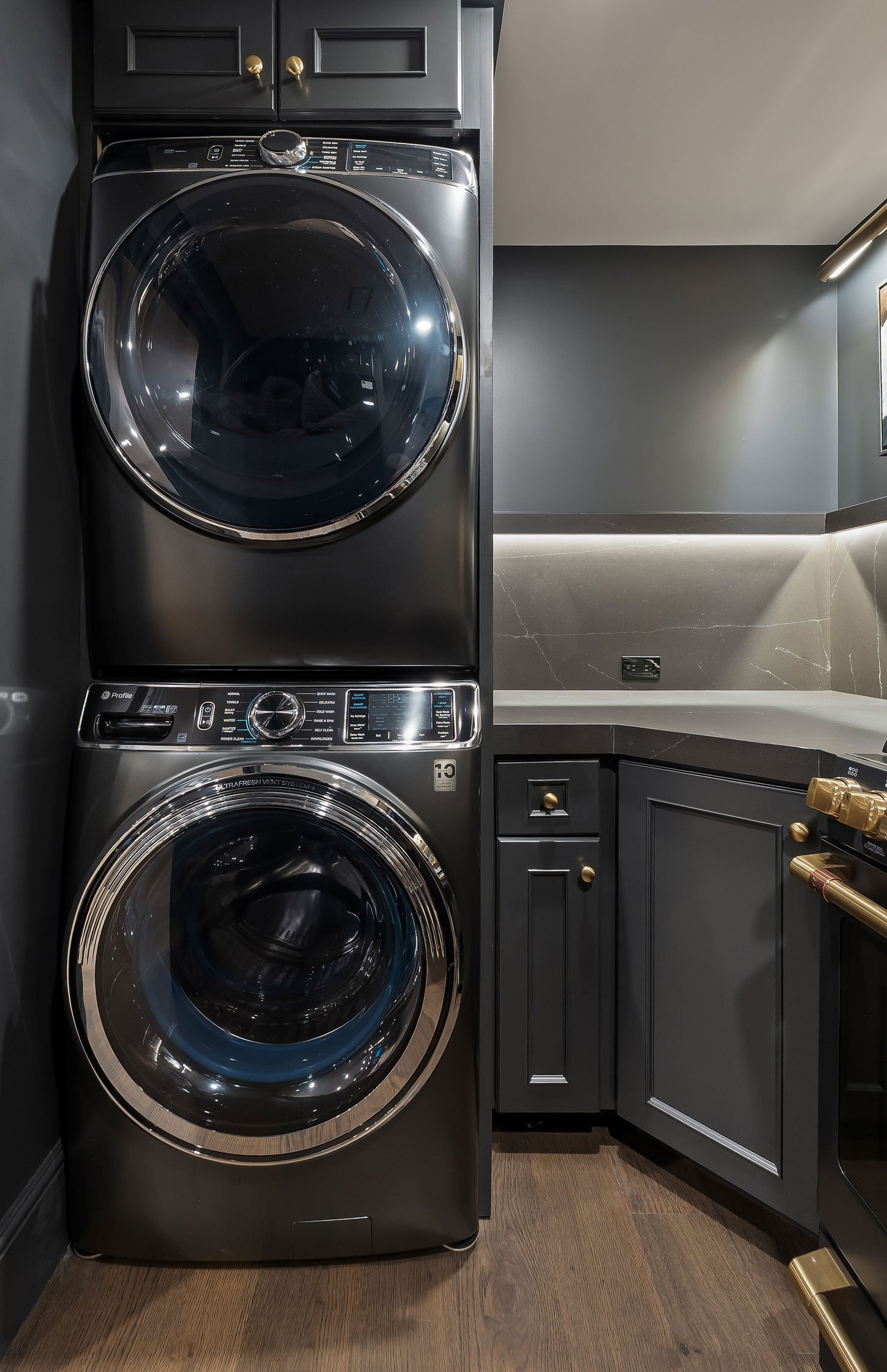 Stacked washer and dryer integrated into custom basement cabinetry beside a compact entertaining kitchen.