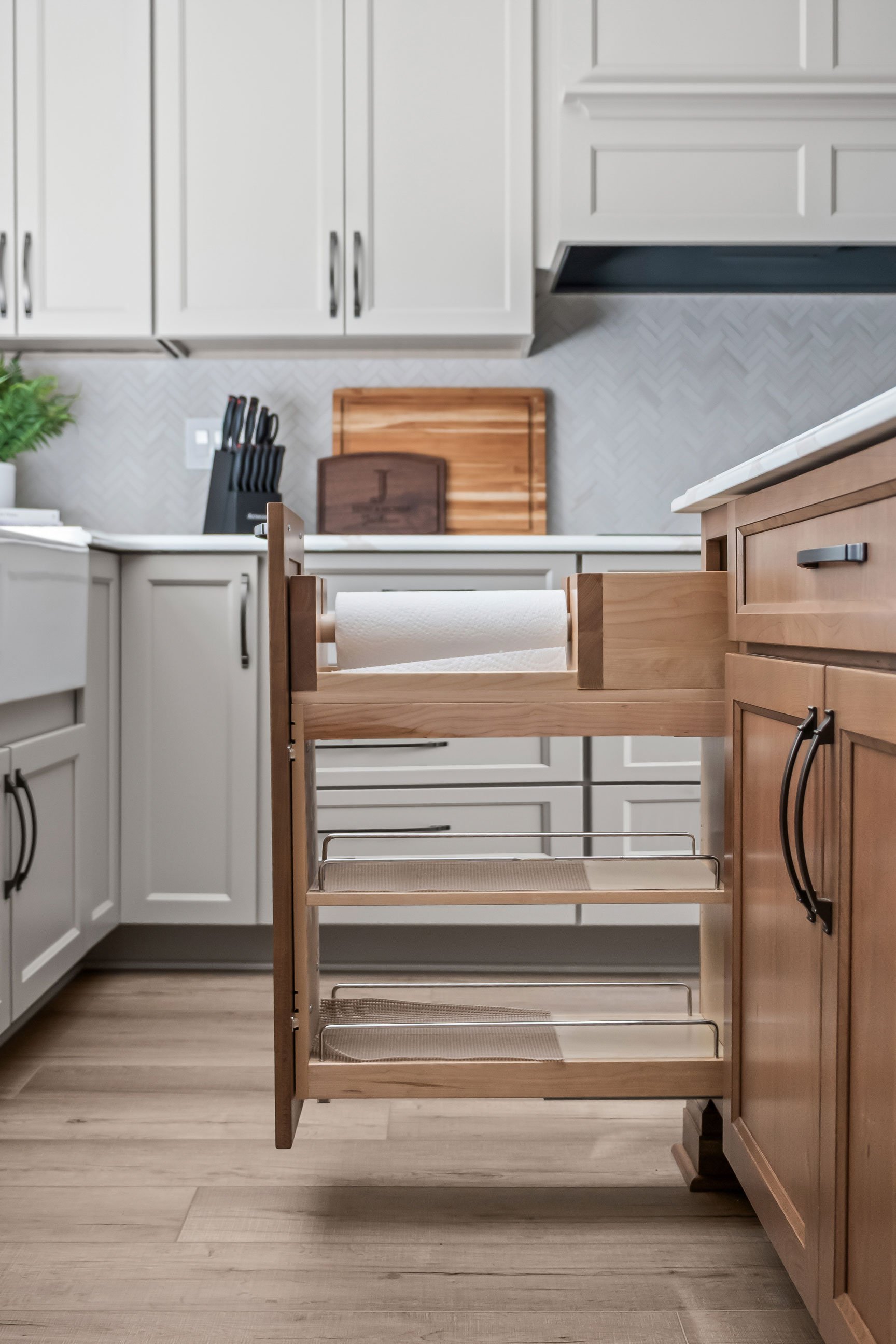 A pull-out cabinet organizer holding a roll of paper towels.