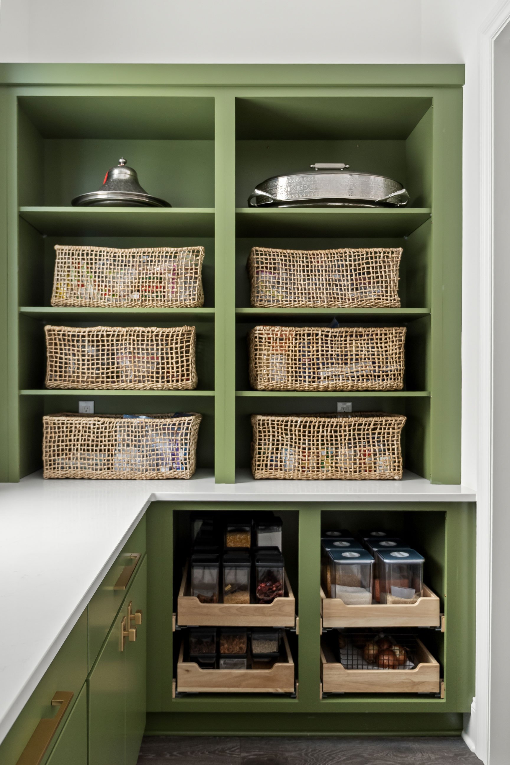nterior prep kitchen with green cabinetry and organized wicker baskets and pull-out drawers.
