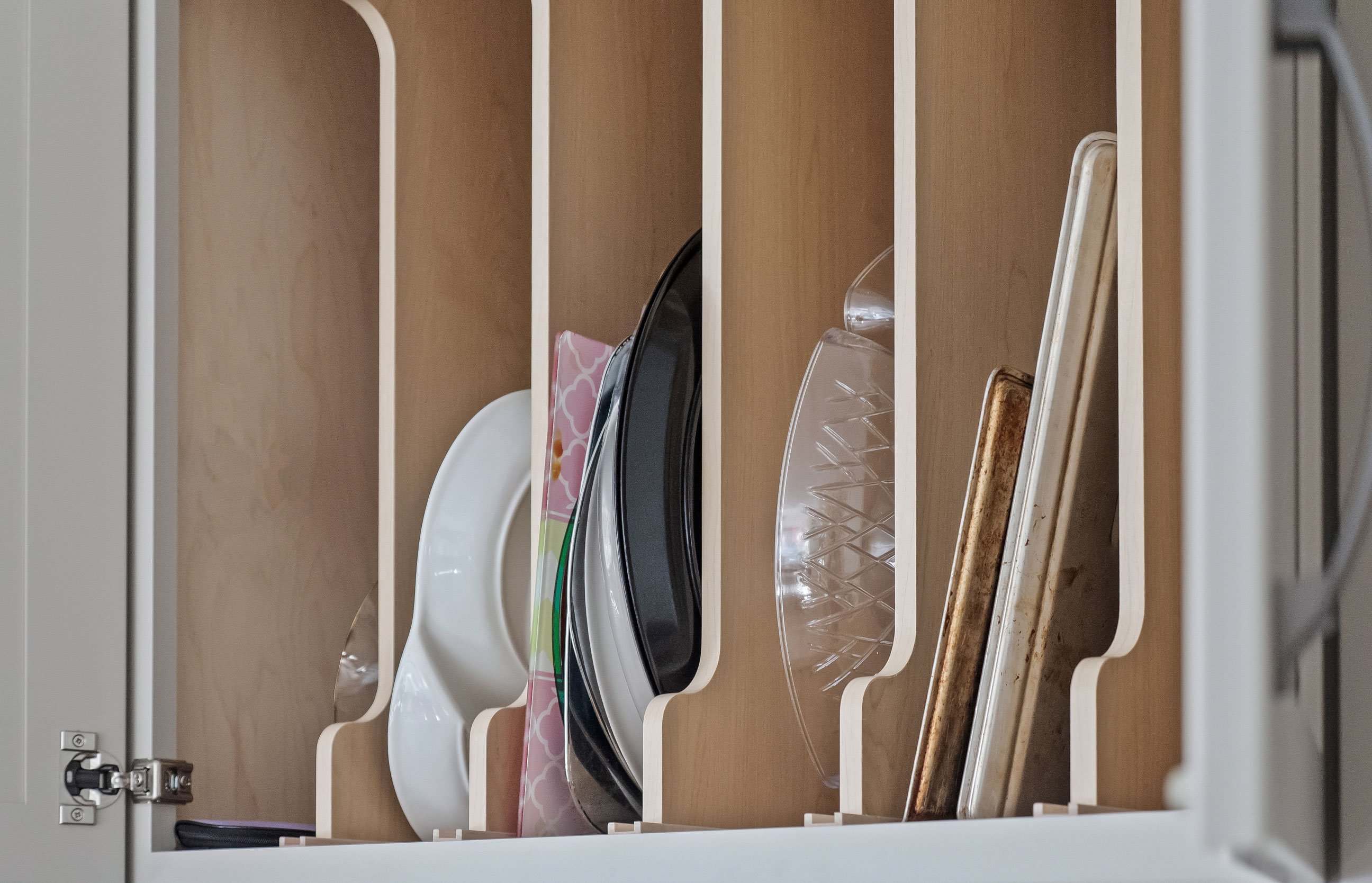 A vertical tray divider storing platters and baking sheets upright.
