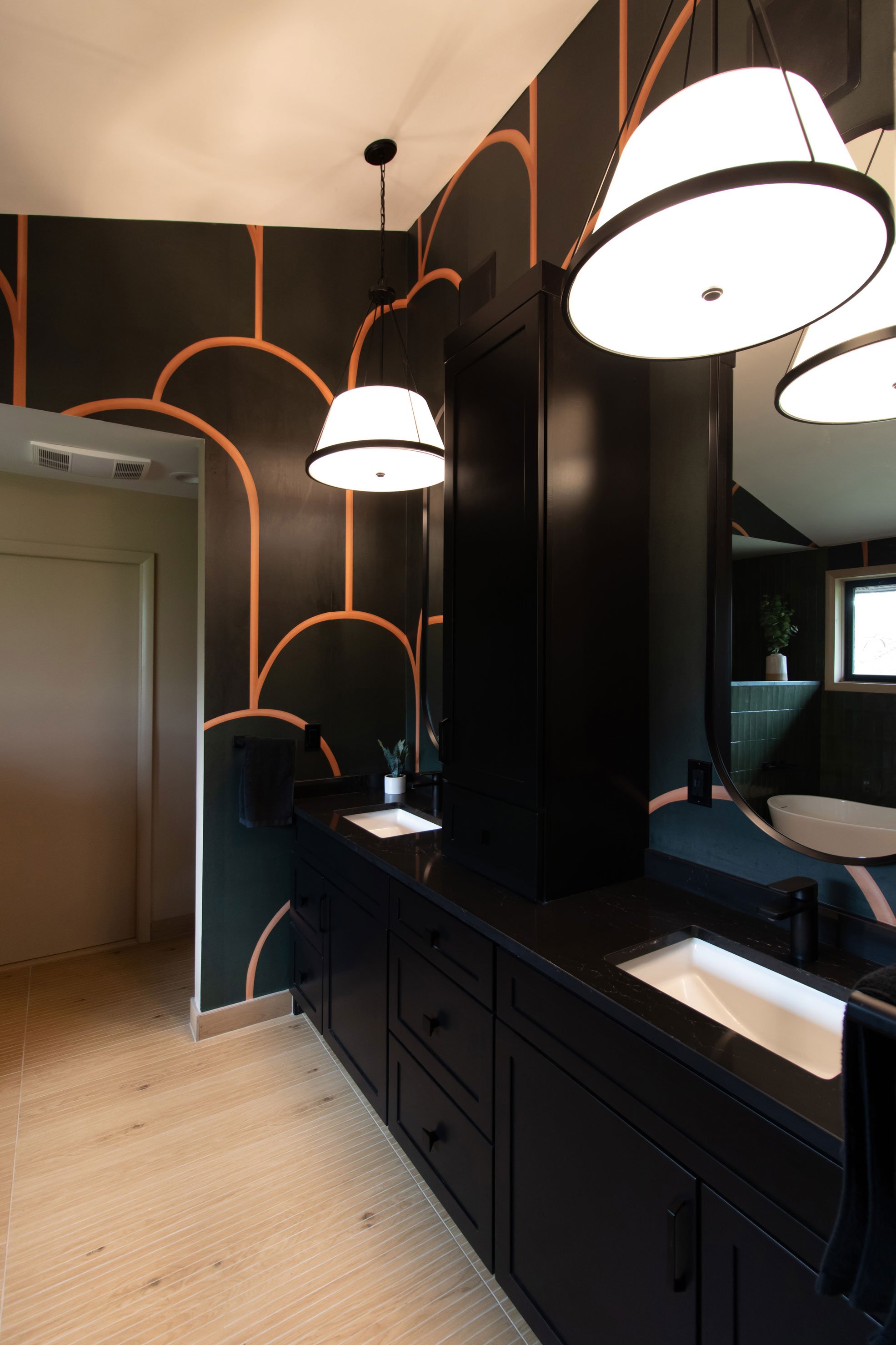 Black double vanity with statement wallpaper and pendant lighting