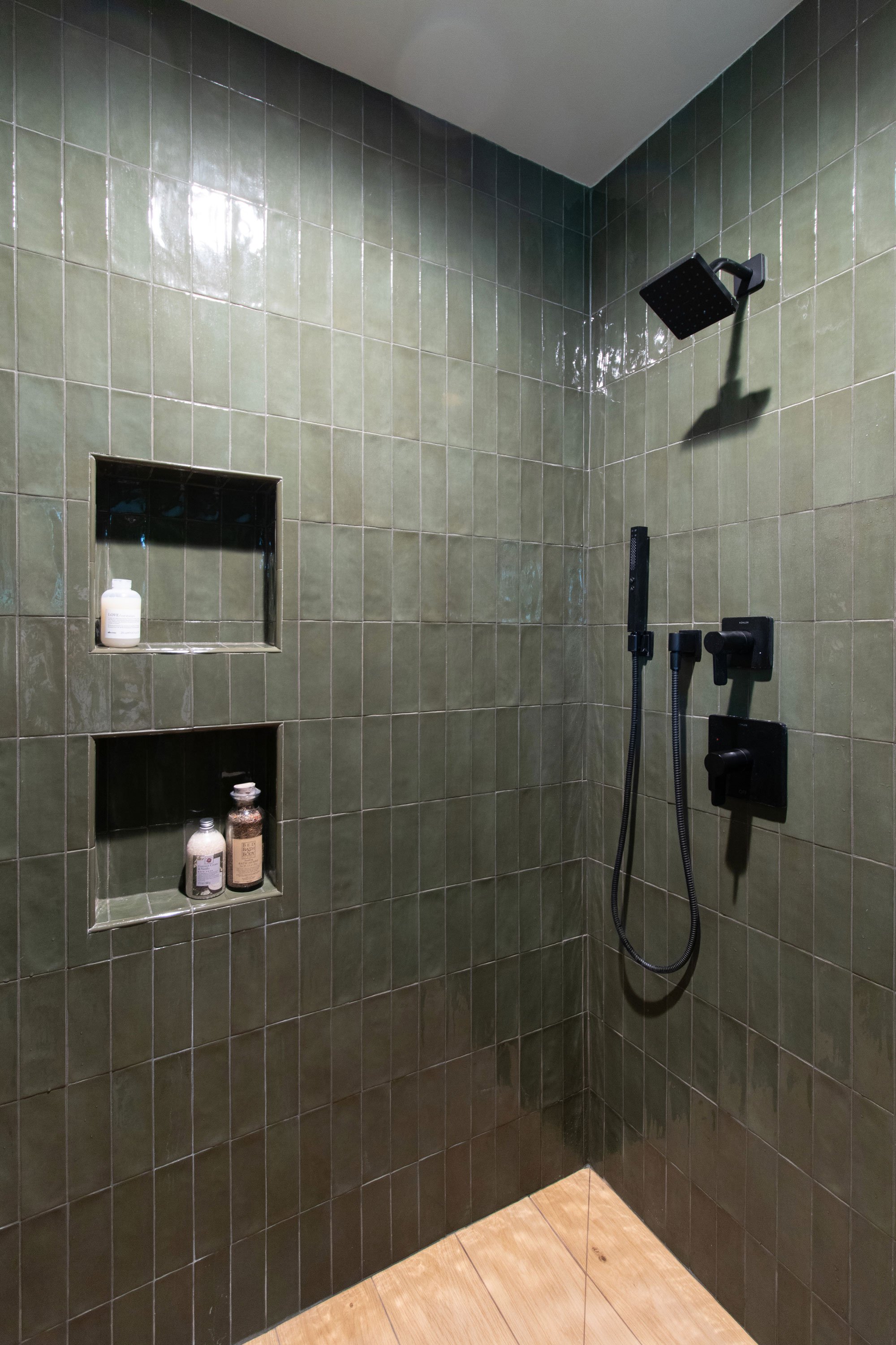 Walk-in shower with green tile and matte black fixtures
