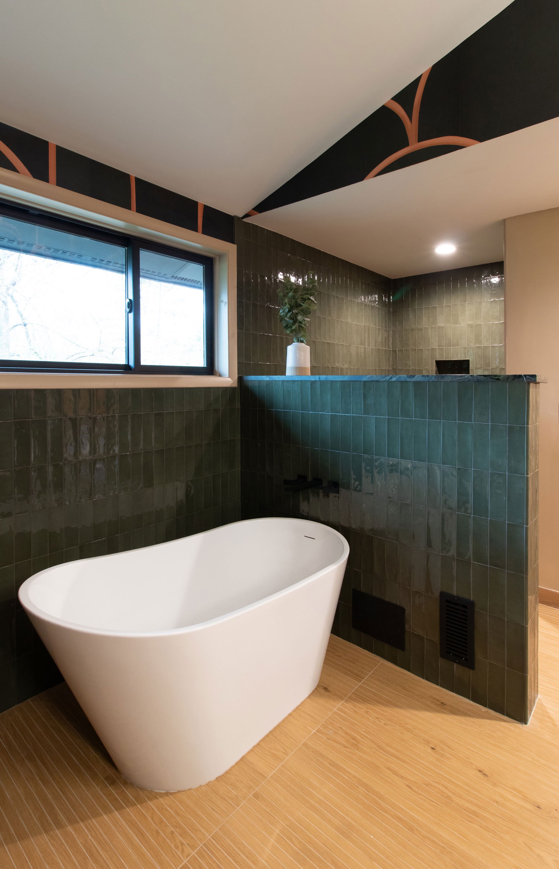Freestanding tub with green tile surround and warm flooring