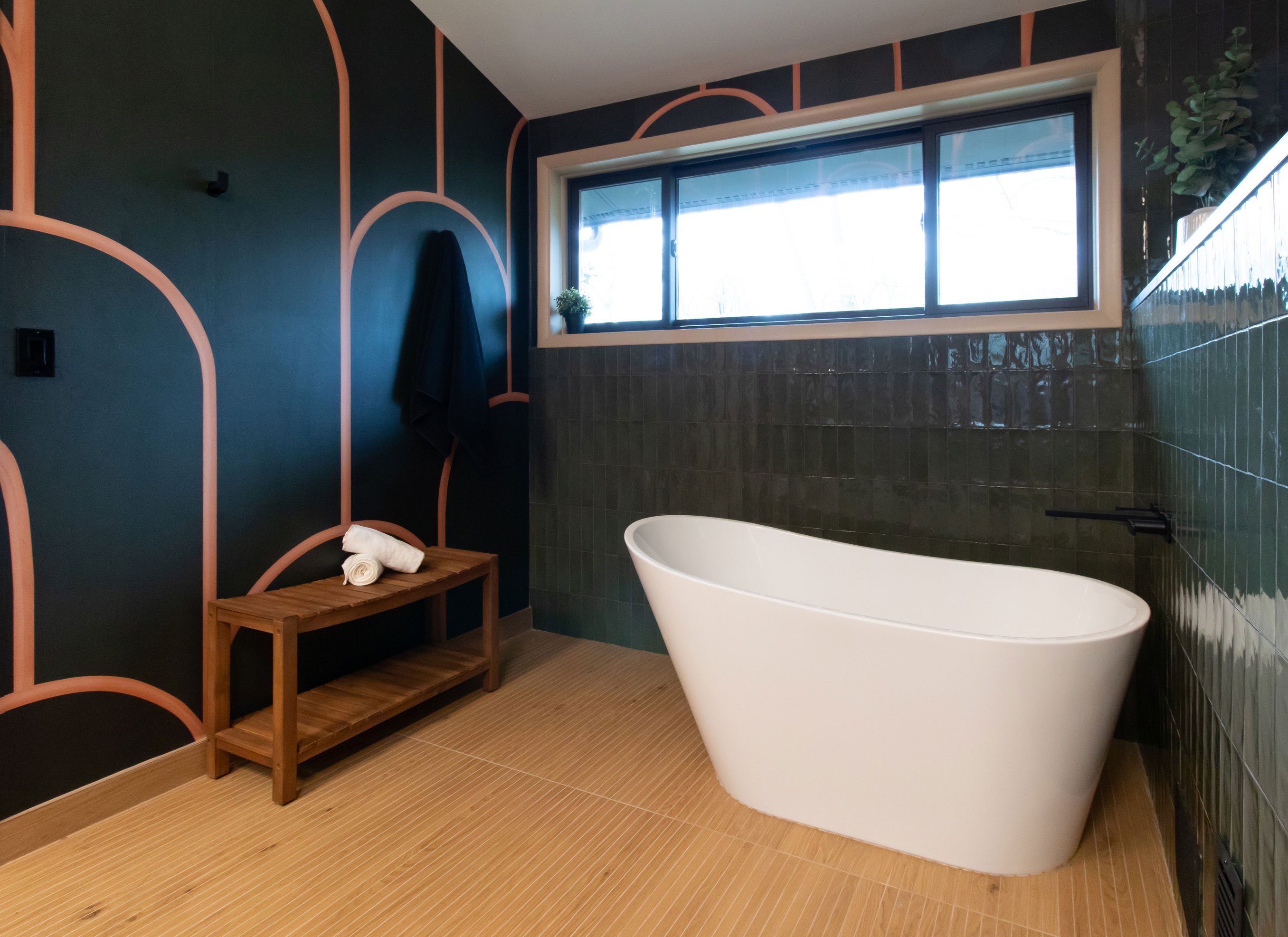 Freestanding tub with green tile surround and warm flooring