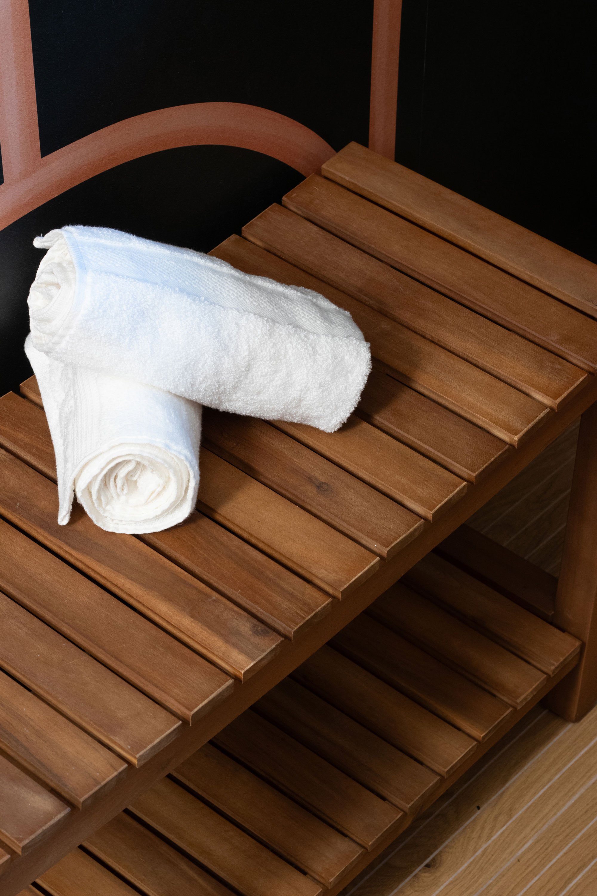 Bench seating detail with wood slats and rolled towels