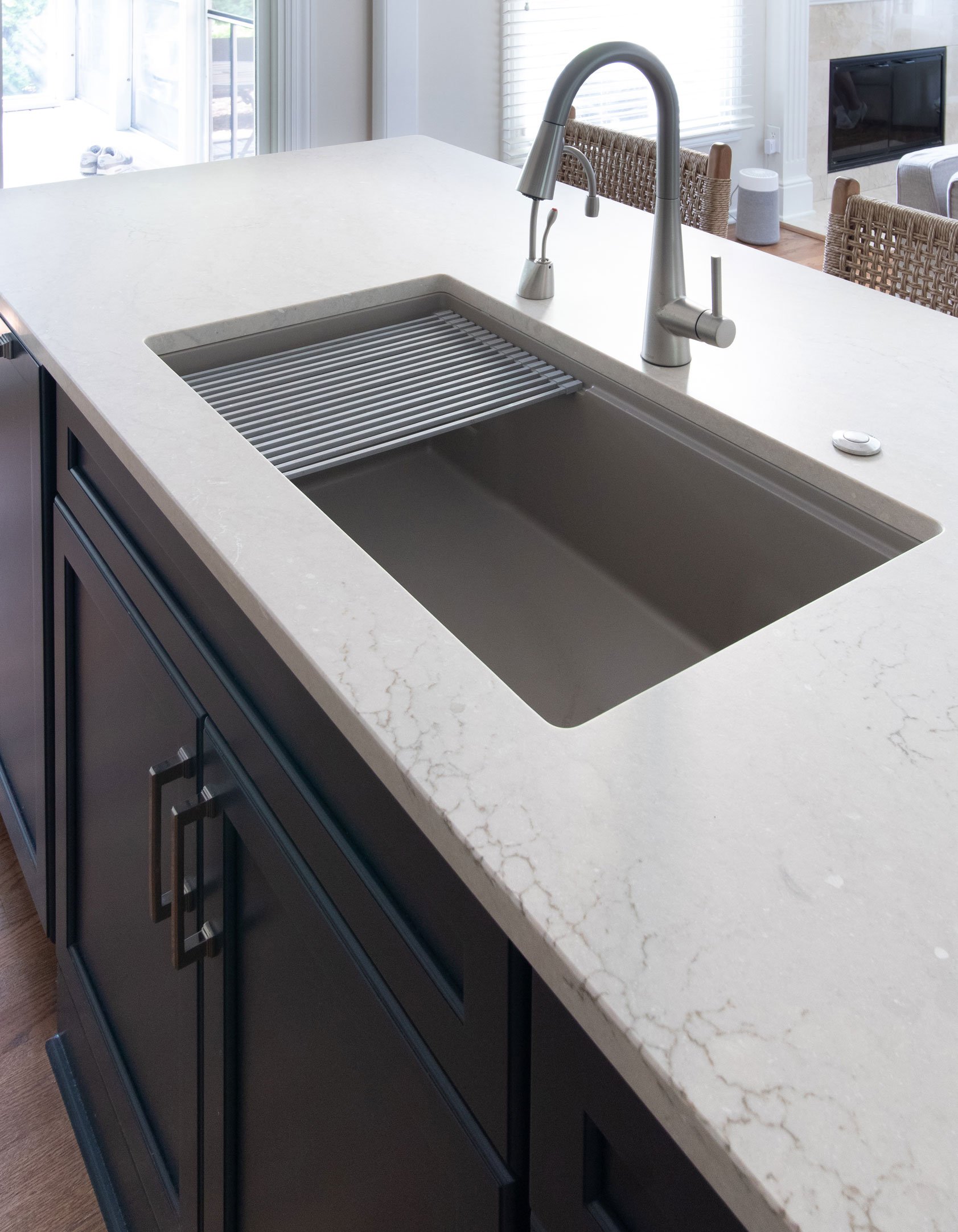 Quartz countertop with integrated workstation sink, drying rack accessory, and brushed nickel faucet.